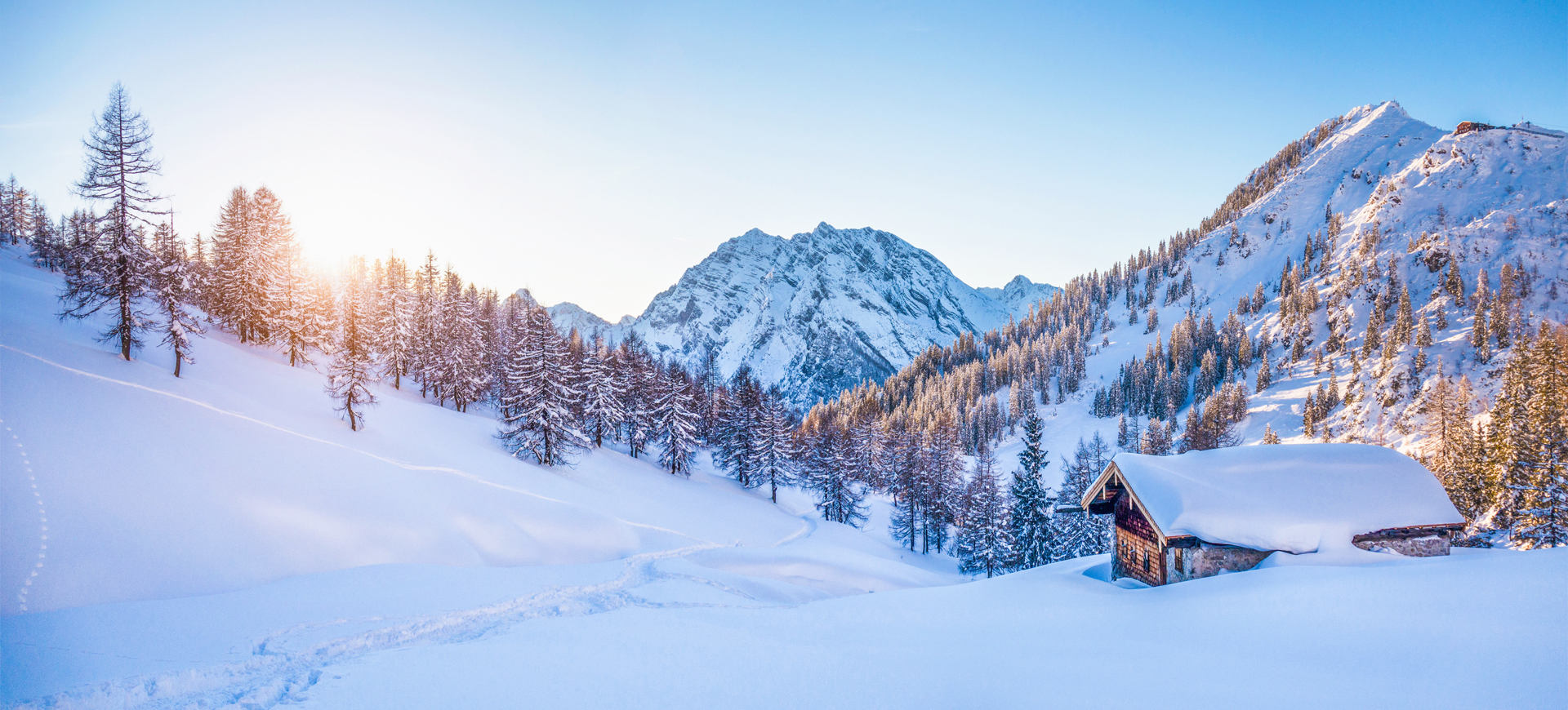 Winter wonderland in the Alps with mountain chalet at sunset