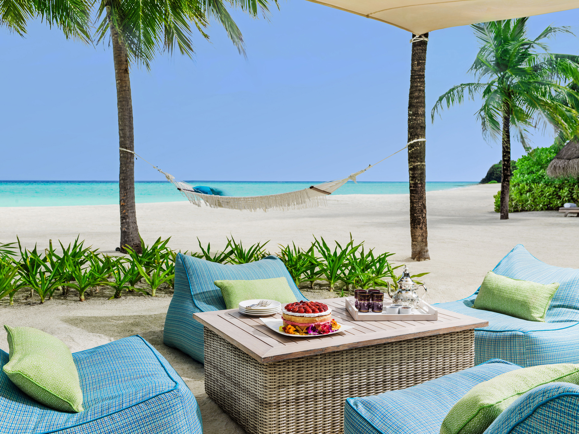 Outdoor comfy chairs around a wicker table at One&Only Reethi Rah
