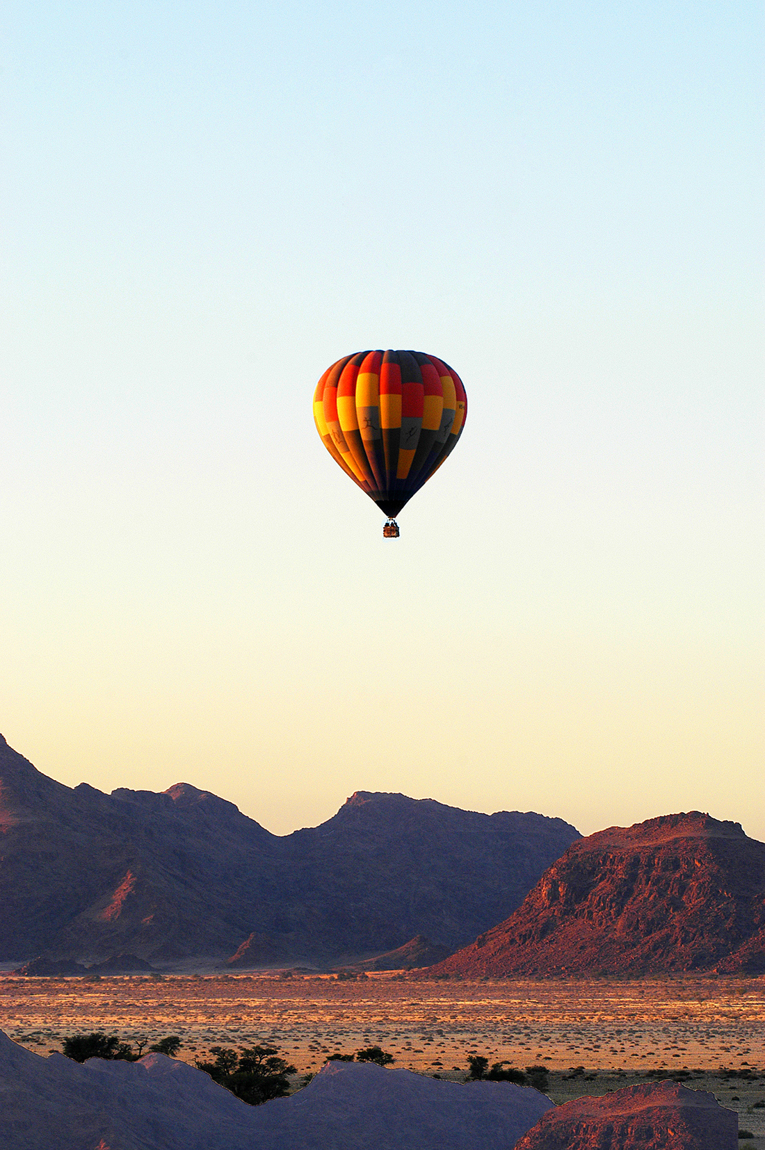 Multicoloured hot air balloon above Namibian desert at sunrise