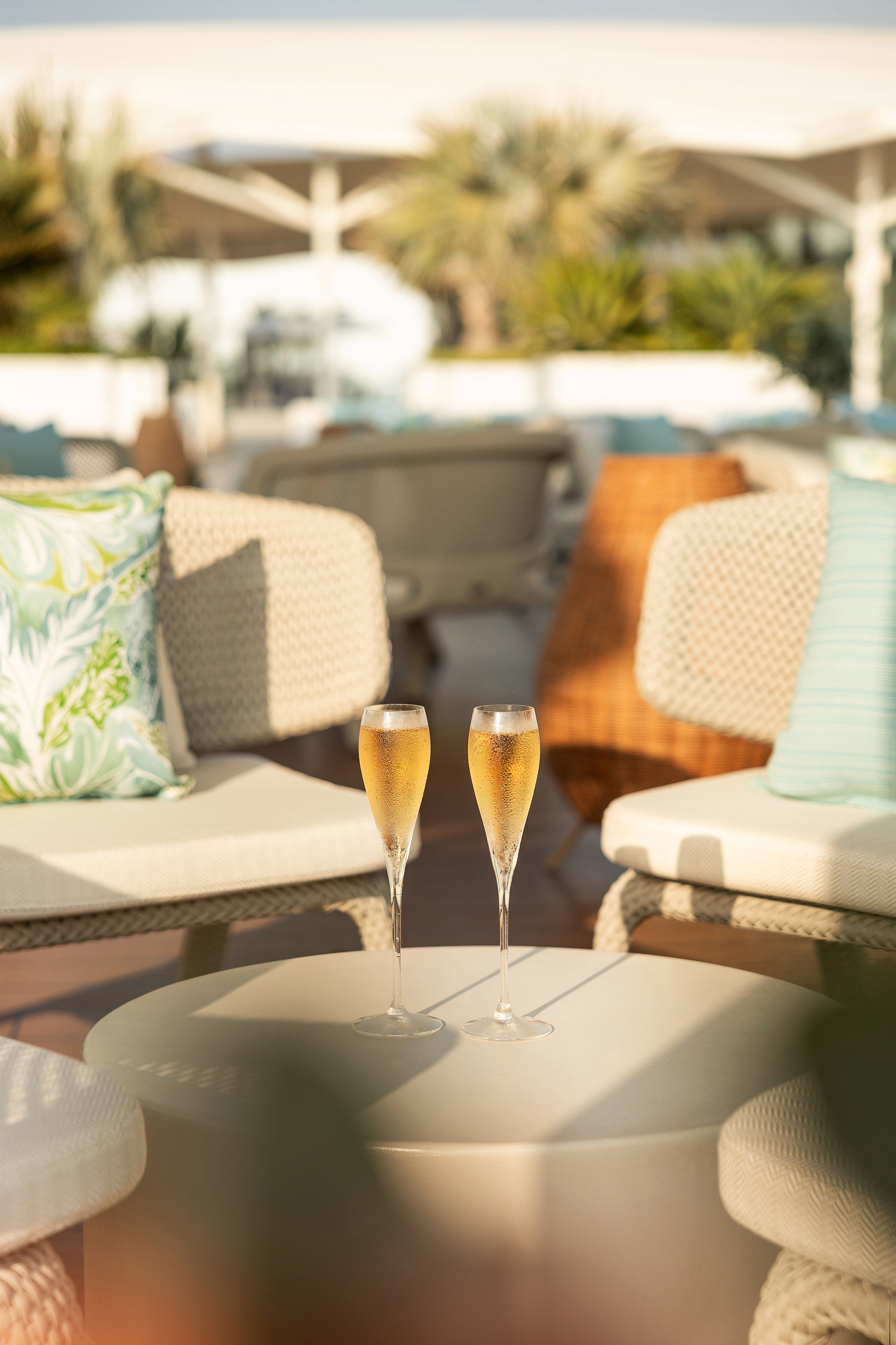 Two glasses of champagne on a low coffee table in the middle of a circle of chairs on the rooftop terrace of Jumerirah Burj Al Arab