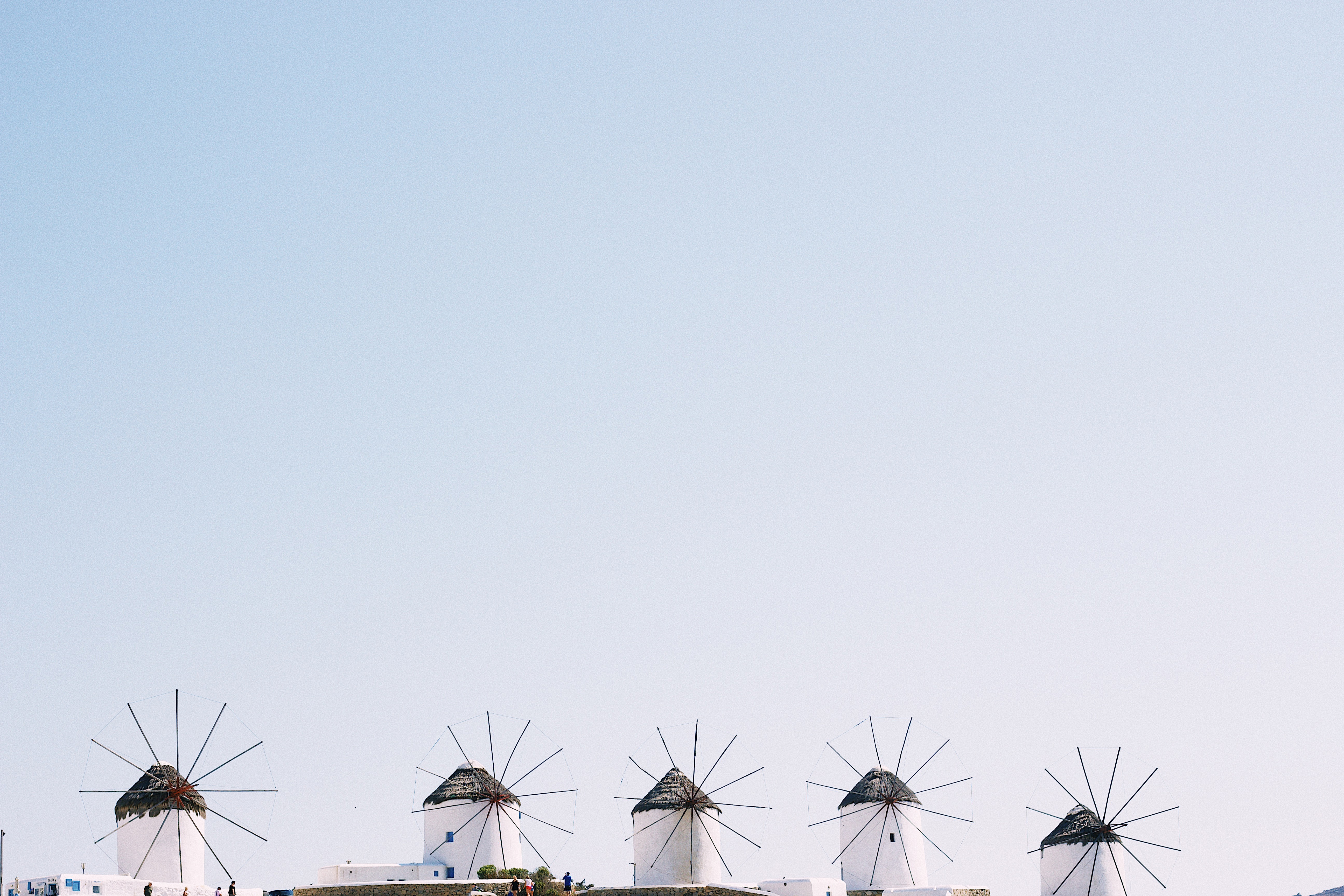 Rustic windmills of Mykonos against a vast background of pale blue sky