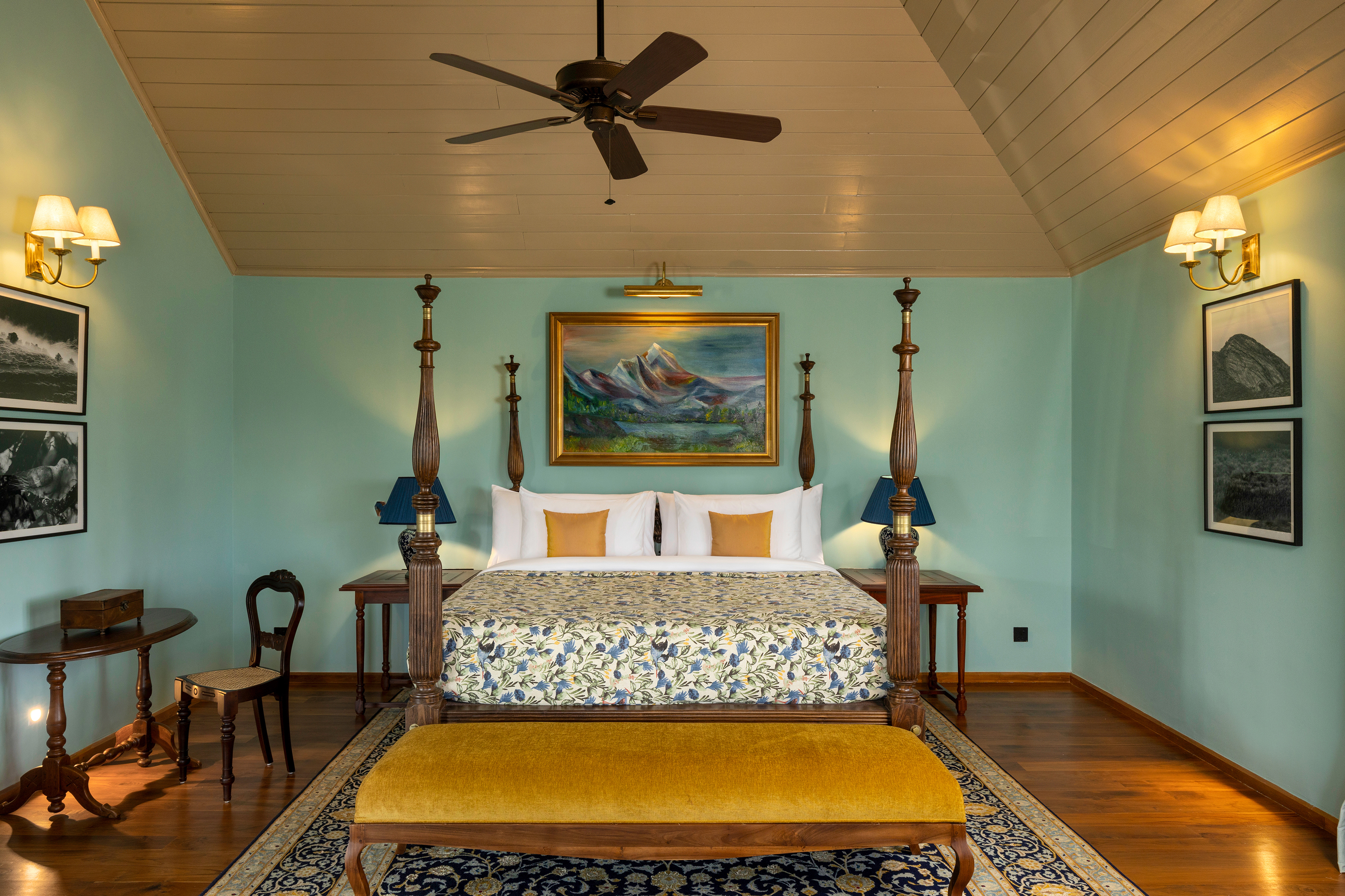 A grand four poster bed in a Lane Suite at Uga Halloowella surrounded by wooden furniture, walls with artwork and panelled ceiling