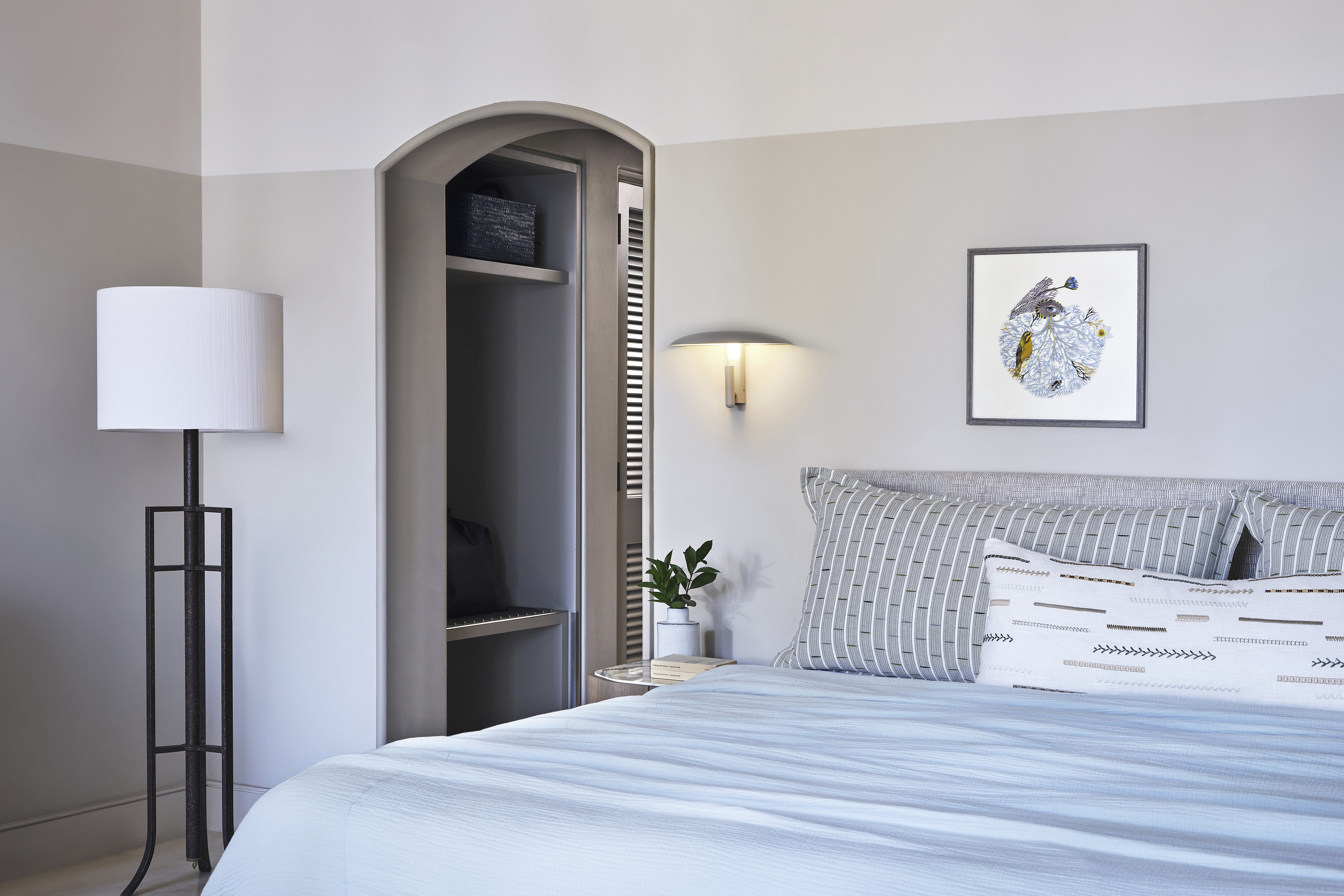 Junior Suite at Anassa in Cyprus featuring a comfy bed with blue and white linens, sleek decor and wall art, and an archway leading to a wardrobe room
