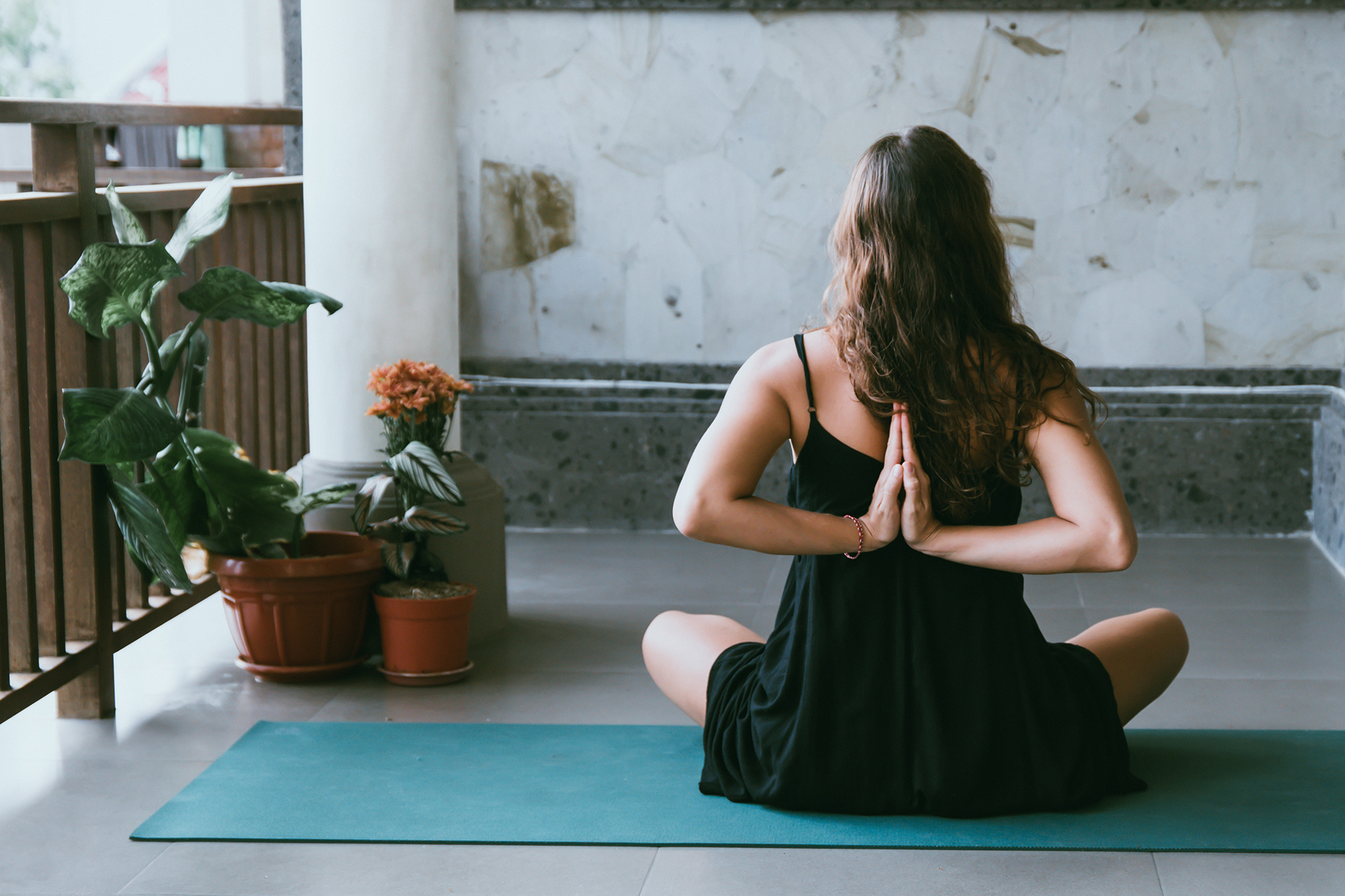 Woman wearing black shirt sitting on green yoga mat 