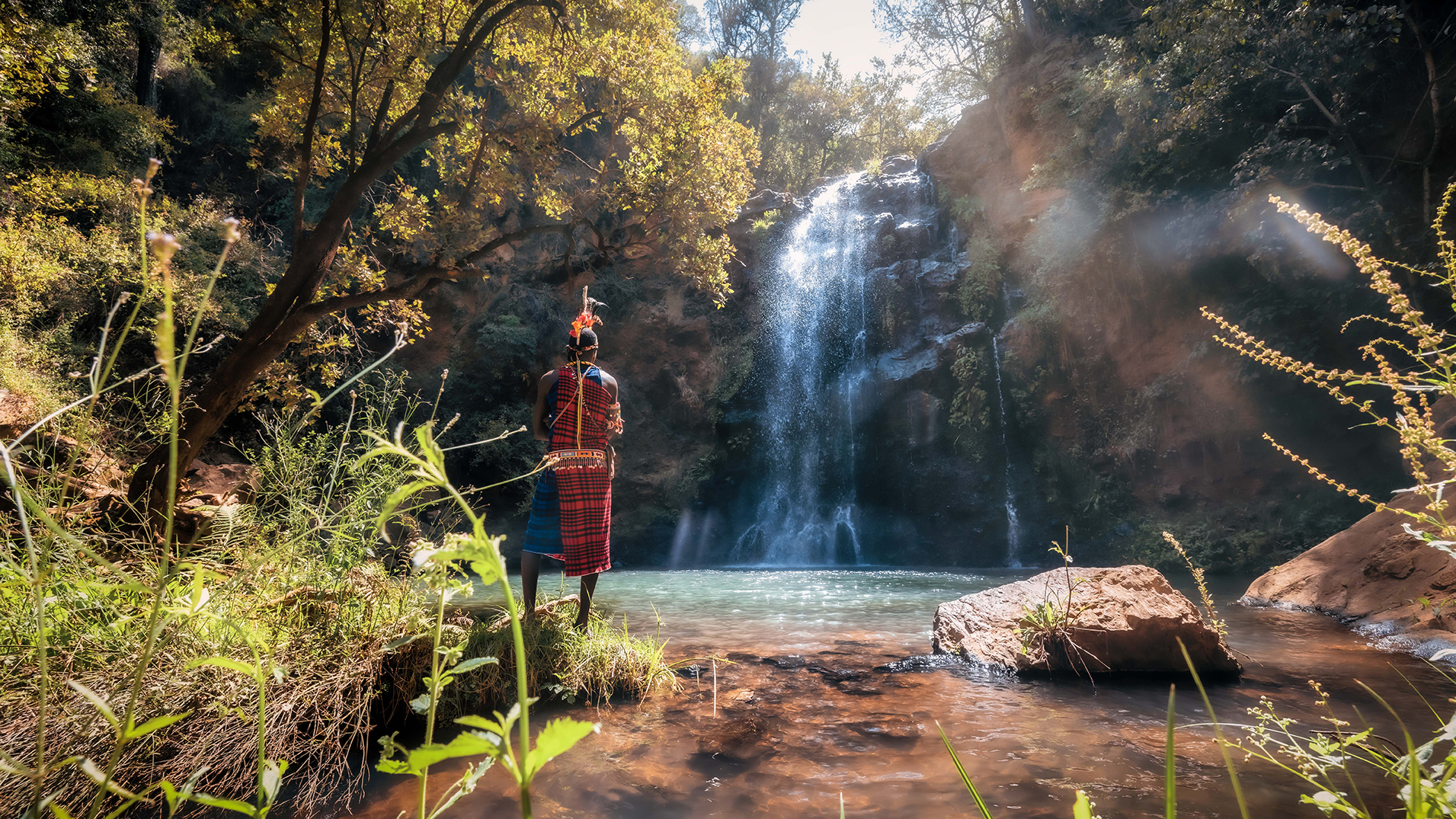 Africa, Kenya, Elewana Kifaru House, Samburu tribe member in front of a waterfall 