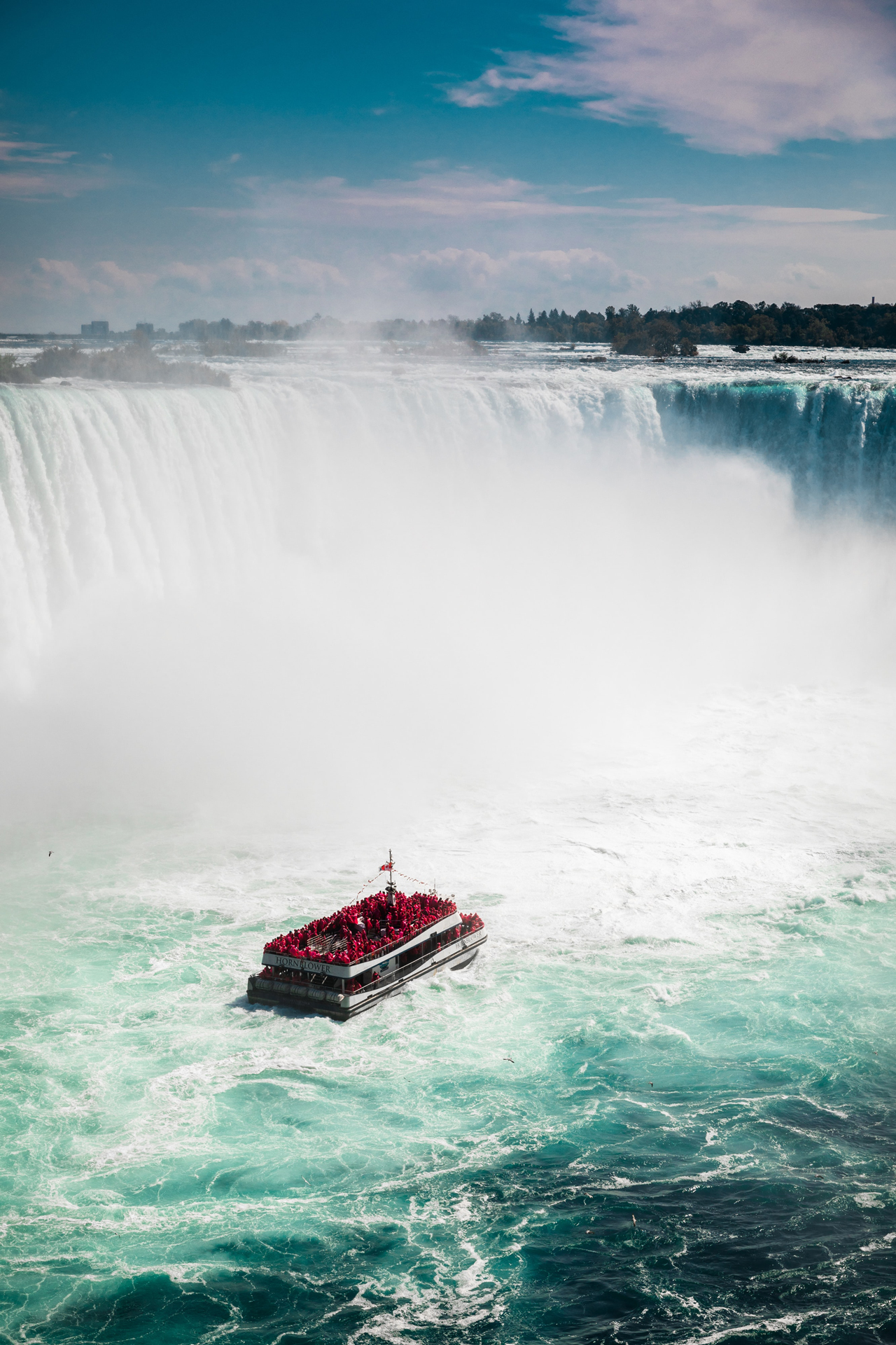 A waterfall with a tourist boat in the water below
