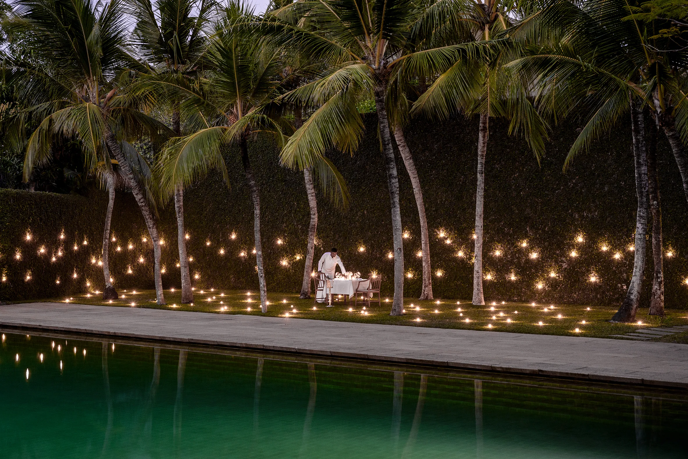 Romantic private outdoor dining setup at Amangalla Sri Lanka, surrounded by palm trees and soft evening lights beside a serene pool.