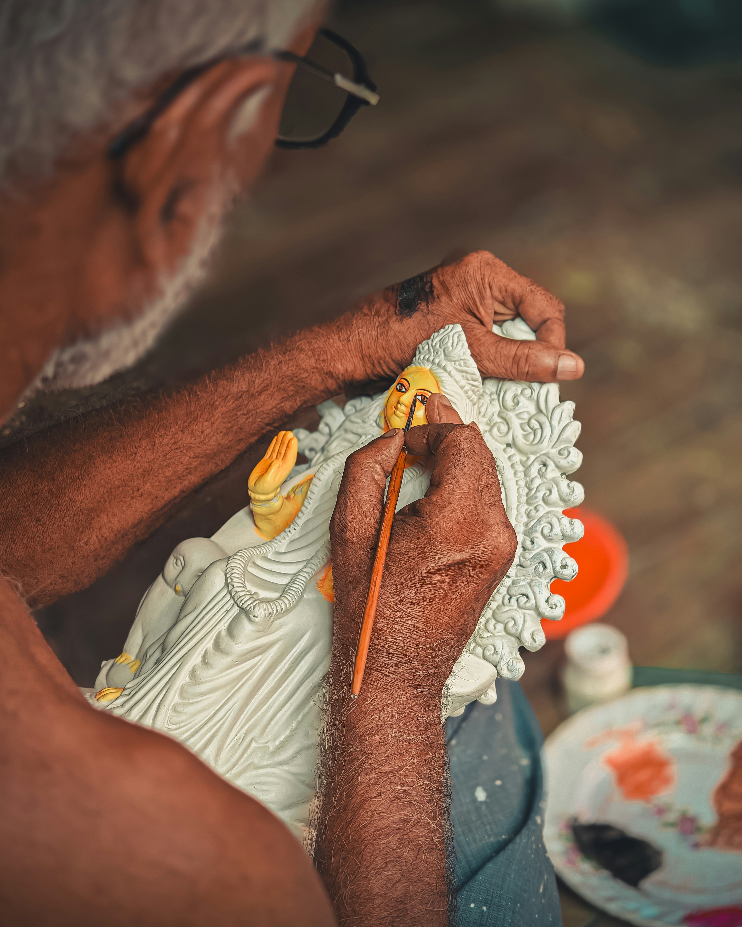 Artisan carefully painting intricate details on a small handcrafted statue using a fine brush in Sri Lanka.