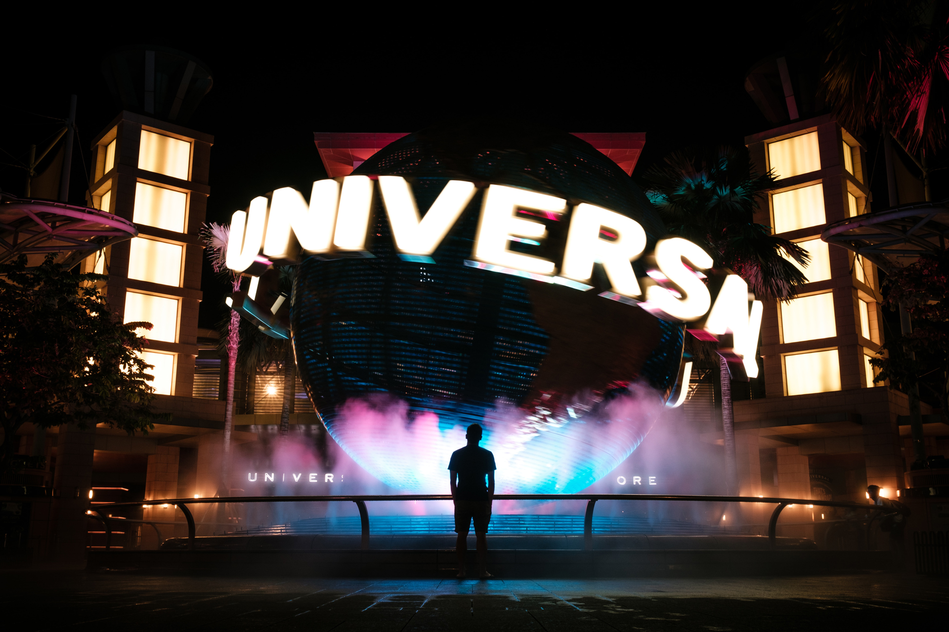 A person stood in the dark in front of the universal studios sign
