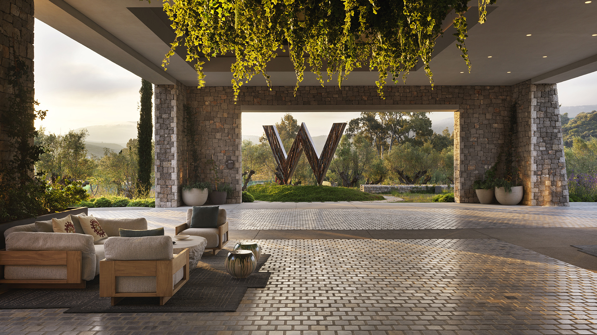 Open plan lobby with ceiling greenery and W statue outside at W Costa Navarino