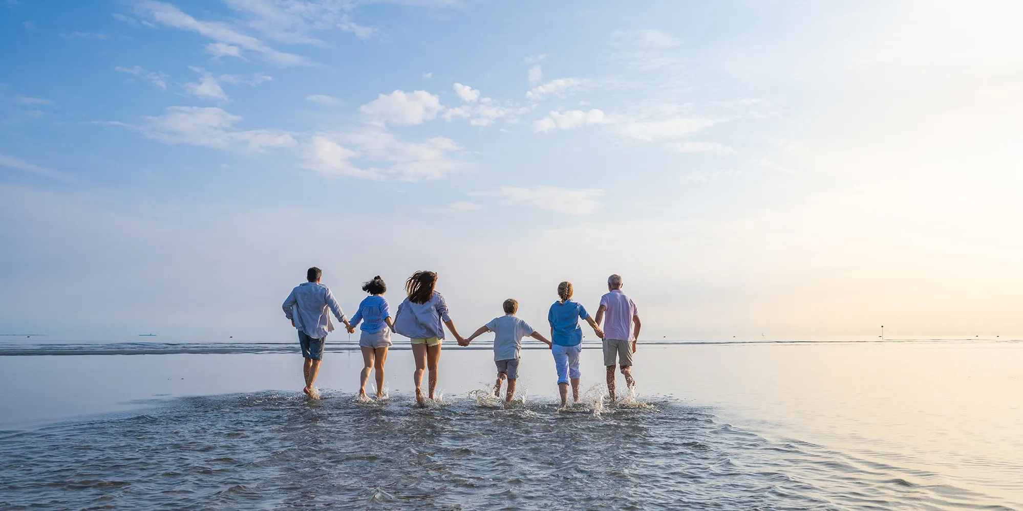 a family running into the sea together holding hands