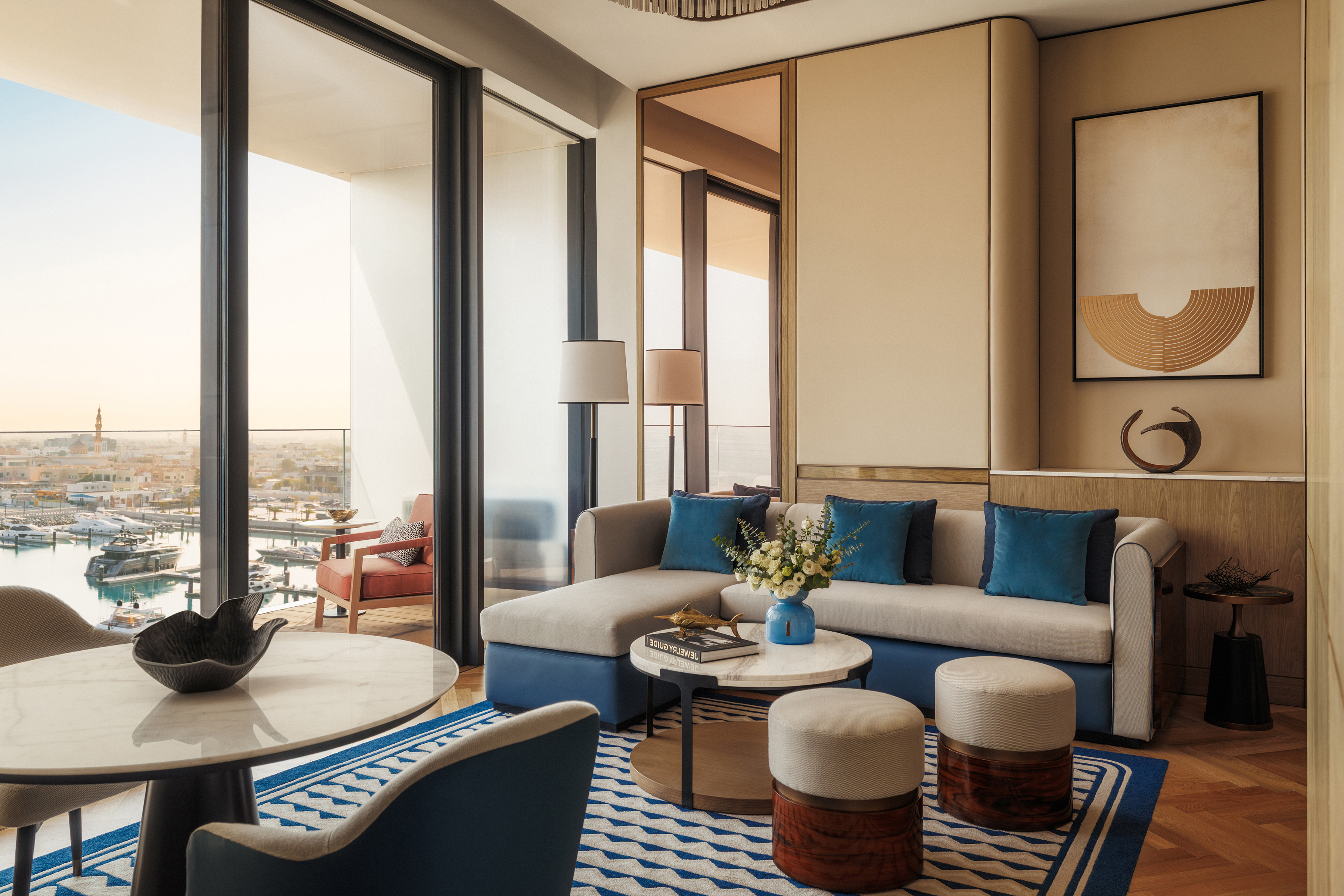 The lounge of a Marina Deluxe Suite at Jumeriah Marsa Al Arab featuring sleek blue and cream furniture 