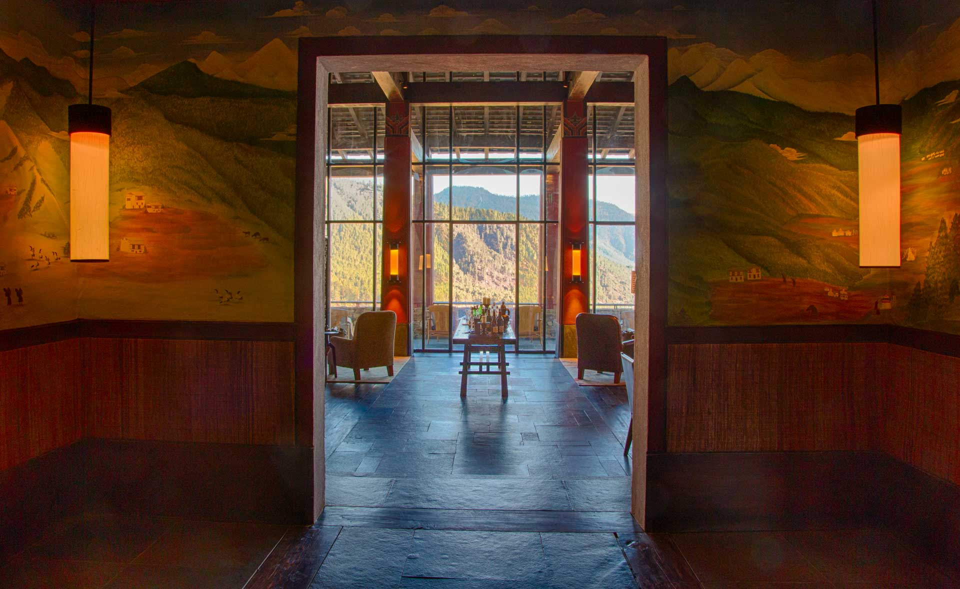 Elegant lounge interior framed by painted walls and large windows, opening onto sweeping mountain views.