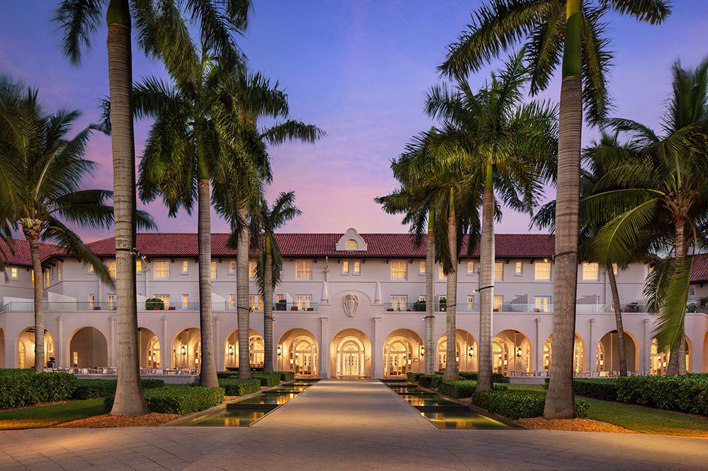 Palm lined driveway leading to the front of Casa Marina lit up at dusk