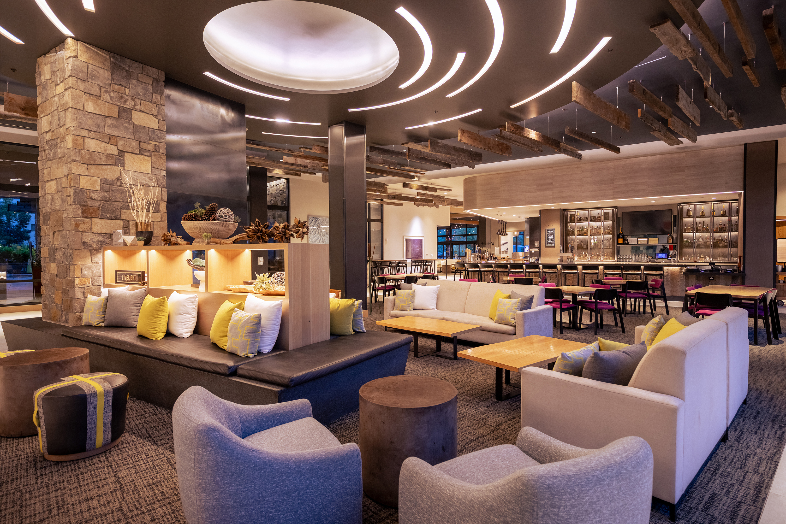 A modern hotel lobby at Limelight Ketchum featuring stylish seating, a central stone fireplace, and contemporary lighting fixtures