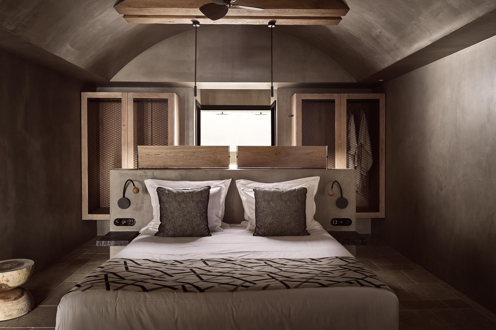 Bed with grey cushions in a suite at Acro Wellness