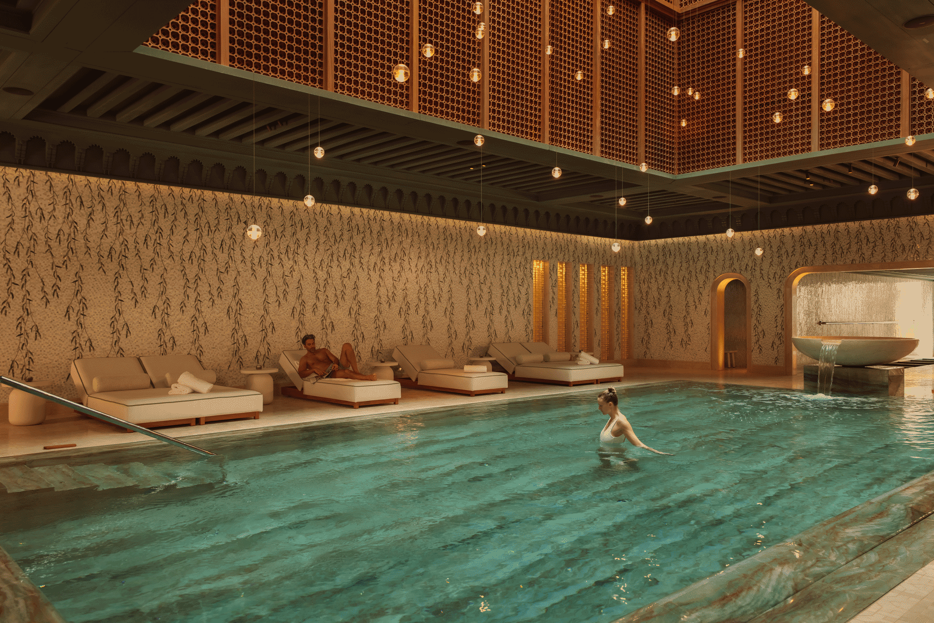 Luxury indoor vitality pool at Royal Mansour Tamuda Bay with loungers, warm lighting, and decorative water feature.