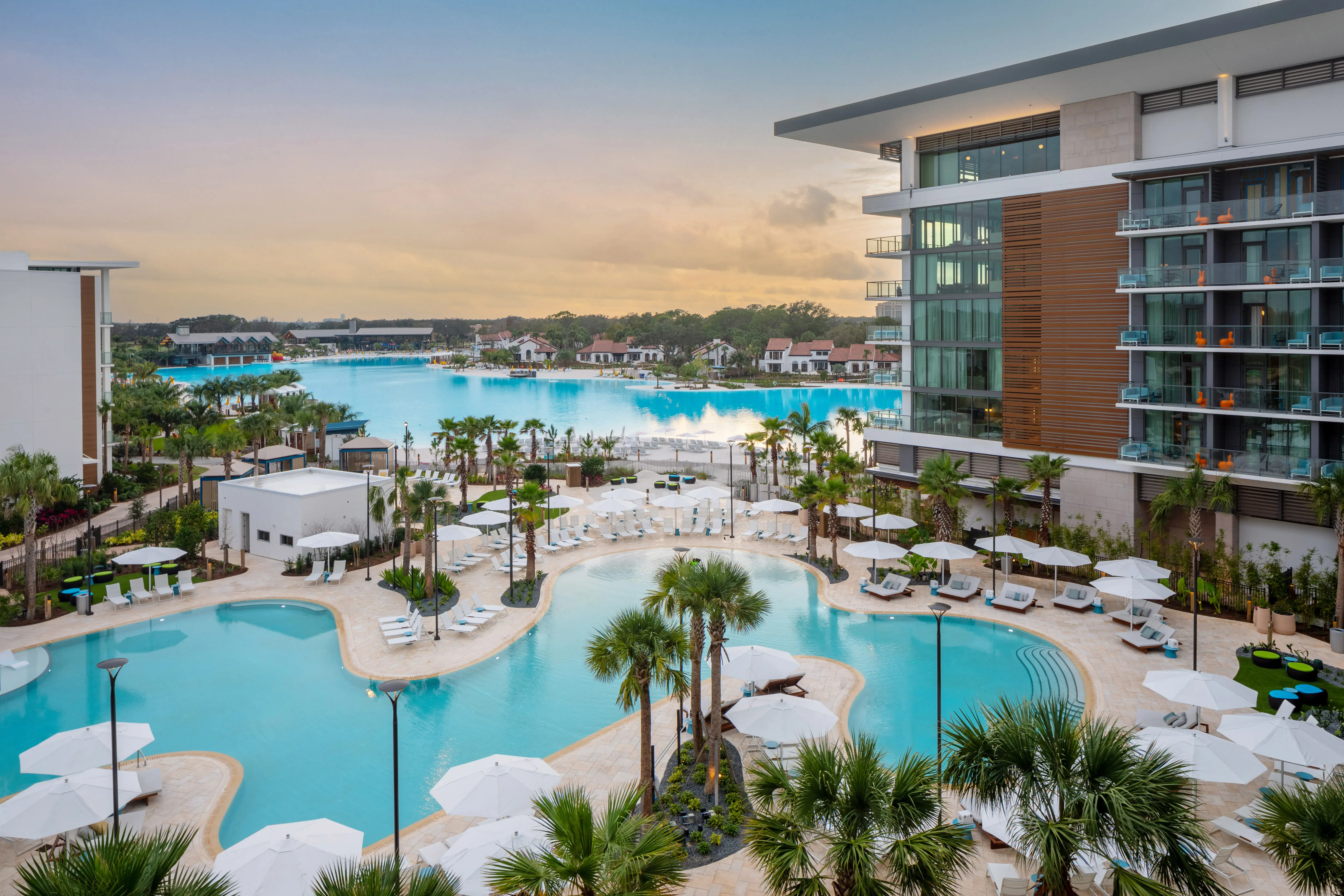 Aerial view of the lagoon, pools, palm trees, and modern resort buildings at Conrad Orlando in Florida.