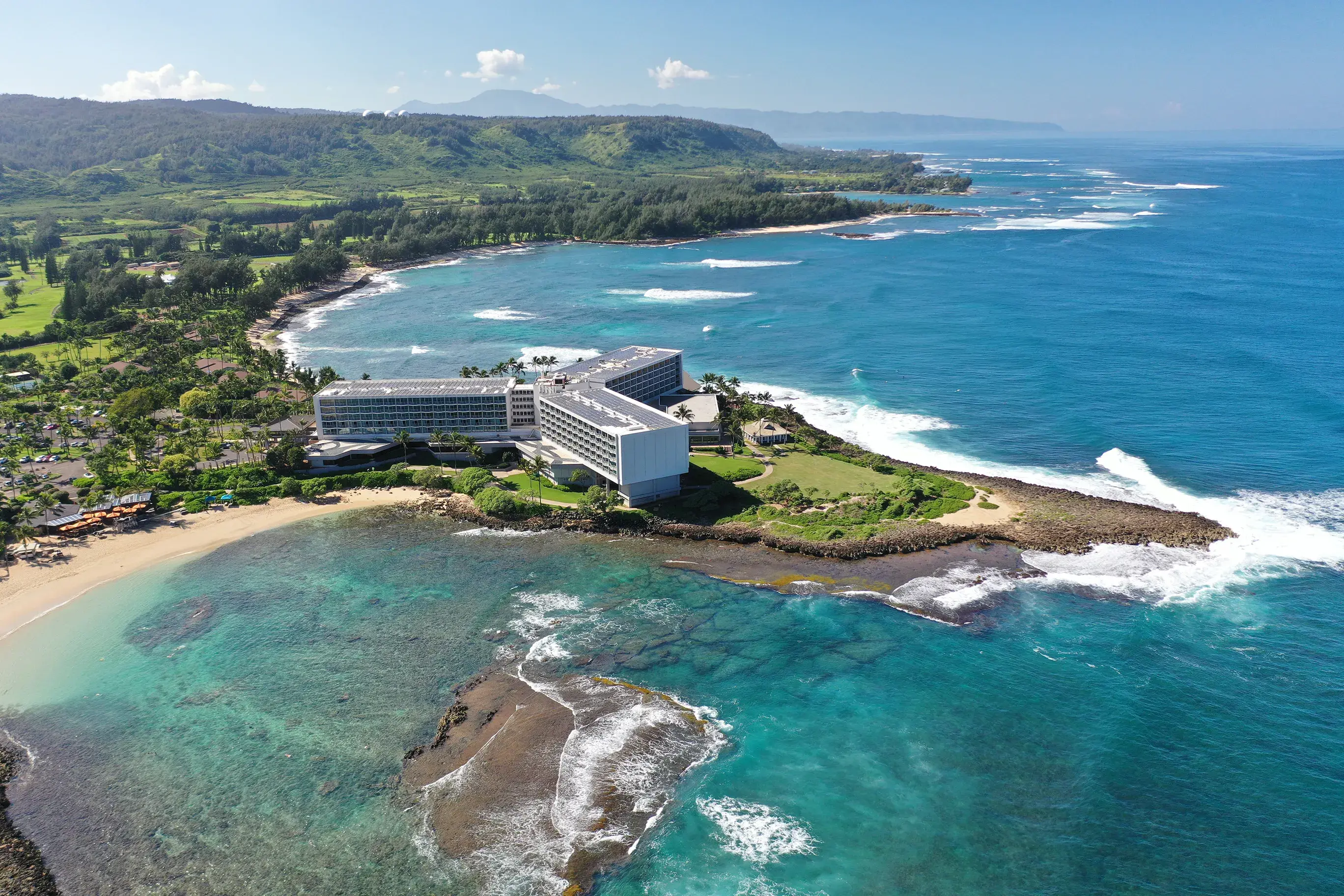 An aerial shot of Ritz-Carlton Turtle Bayshowing the resort on its own peninsula surrounded by ocean and hills behind