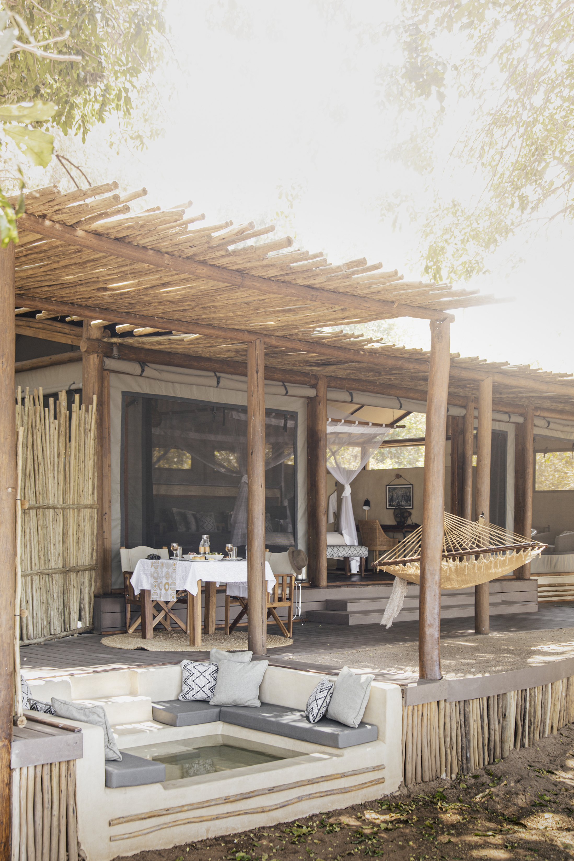 The exterior of a suite at Chiawa Camp featuring a hammock, wallow bench and seating area beneath a woven canopy