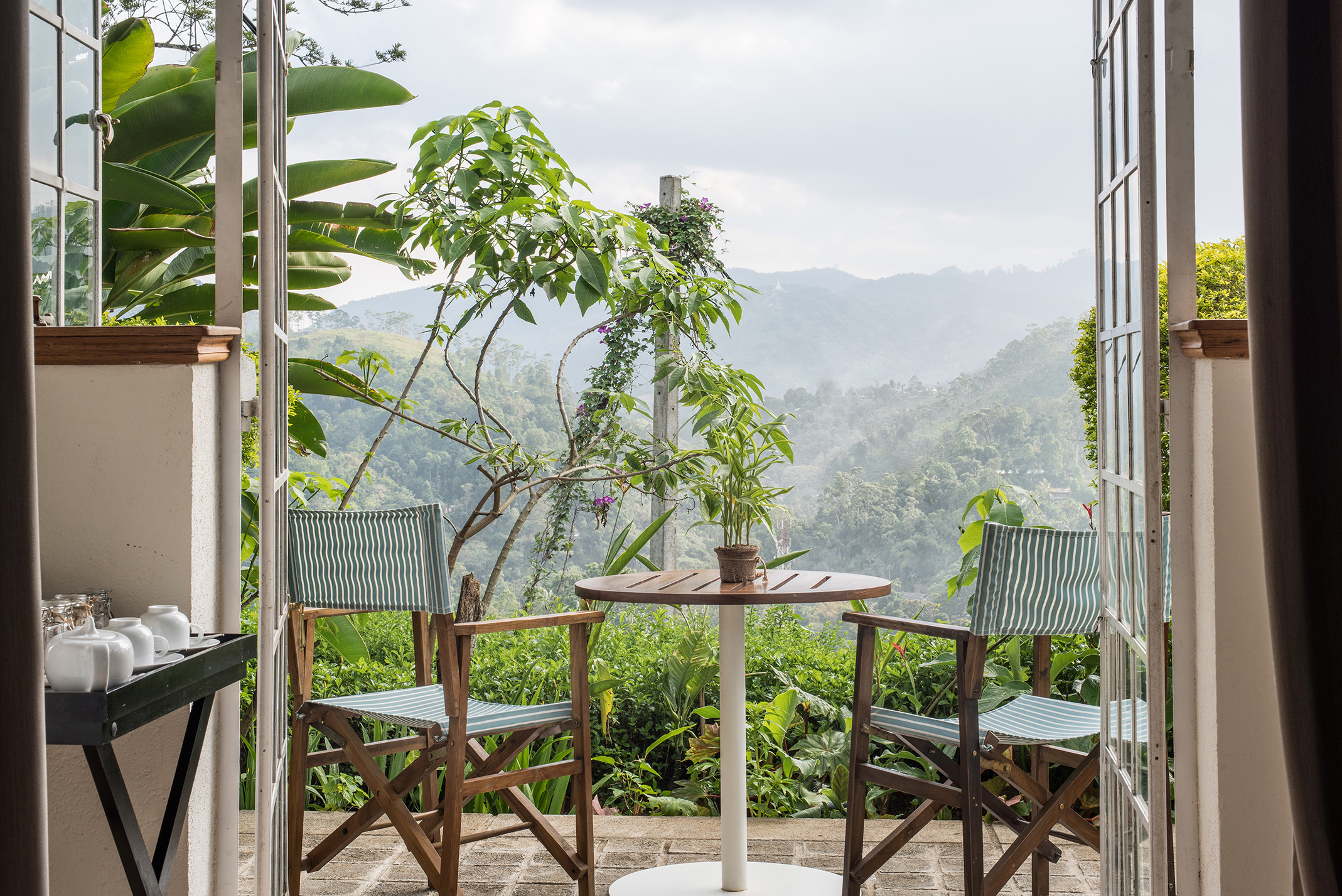 Pretty chair and table set on the terrace of a room overlooking rolling hills