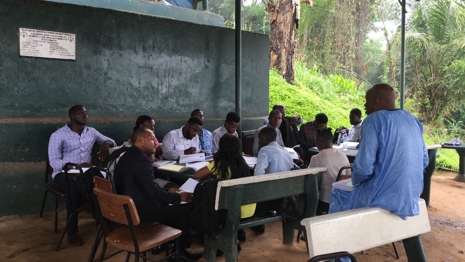 A man teaches a group of students at an outdoor classroom