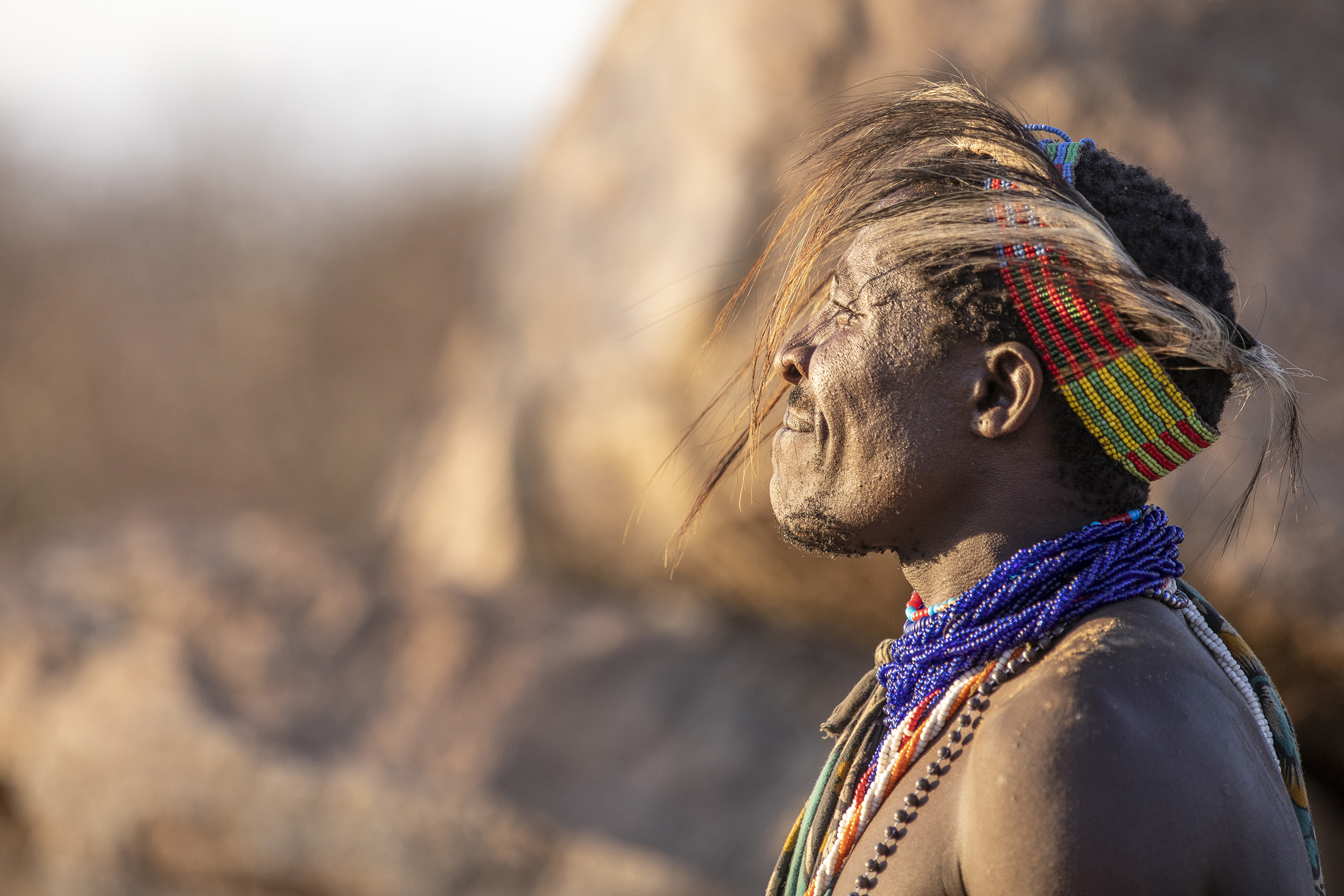 The side profile of a man from the Hadzabe tribe in Tanzania dressed in traditional headwear