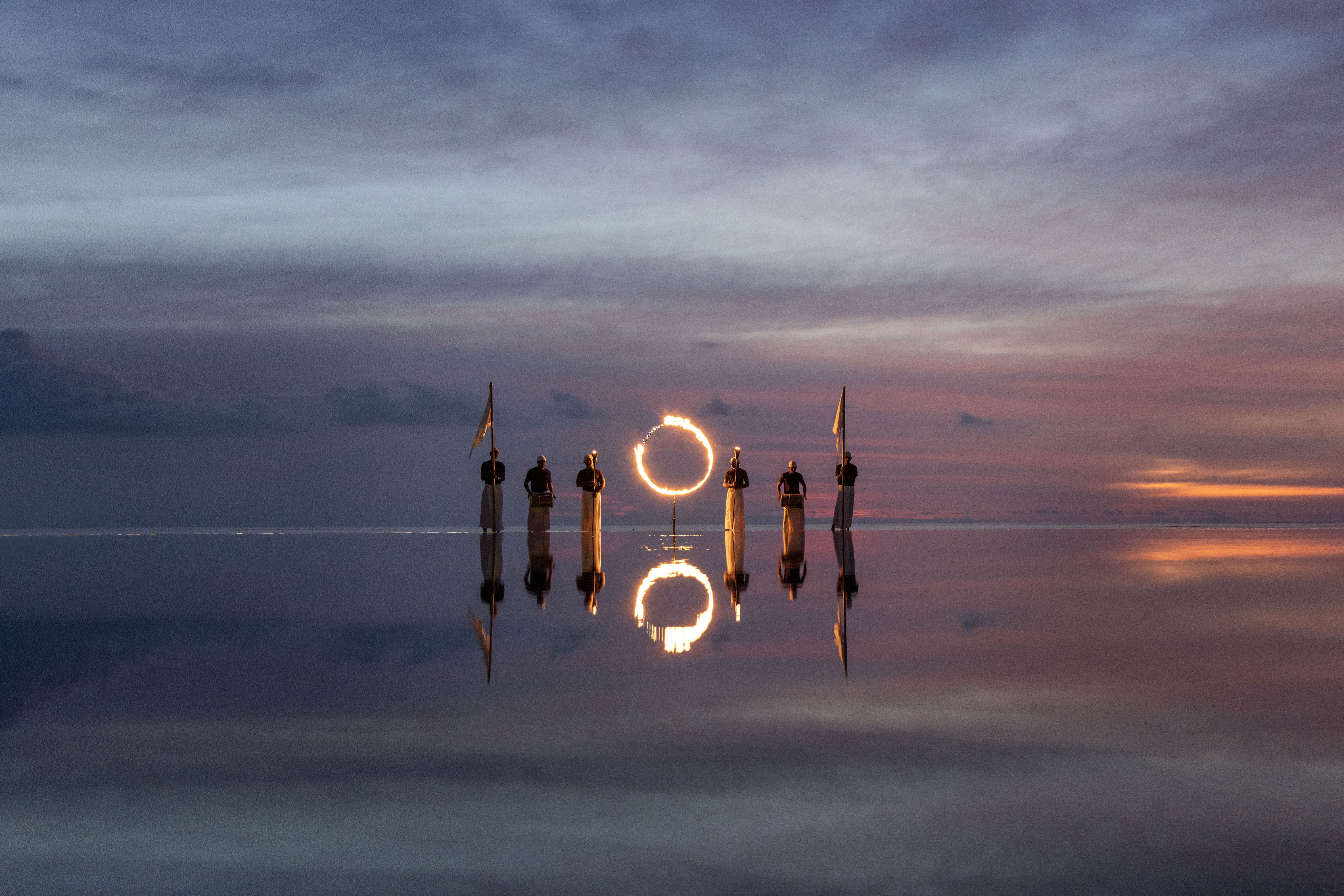 Sunset fire ring at edge of pool with staff members at Ritz-Carlton Fari Islands