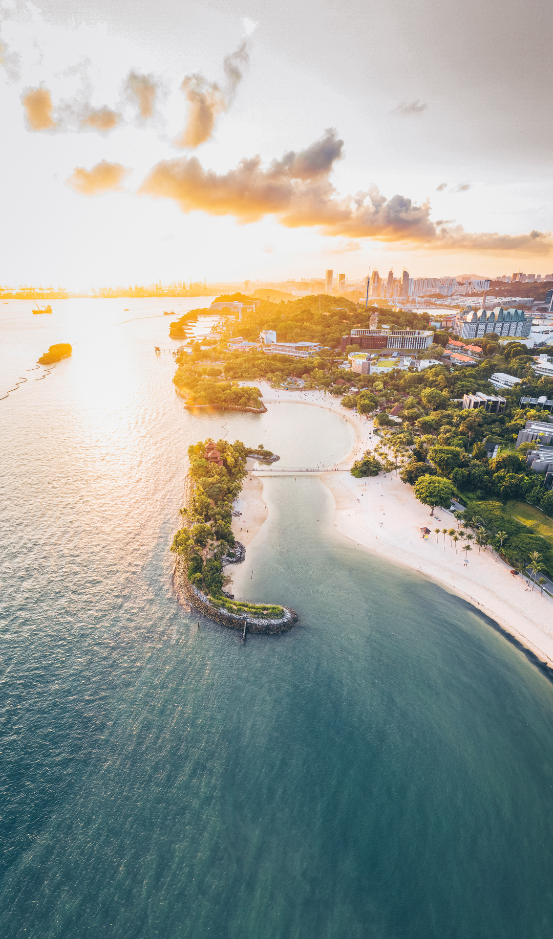 An aerial shot looking down the beach of a coastline city