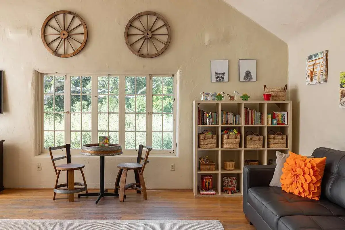 Interior of the Adventure Den kids club at Carmel Valley Ranch in California featuring ranch style furniture and toys on a shelving unit with windows overlooking fields