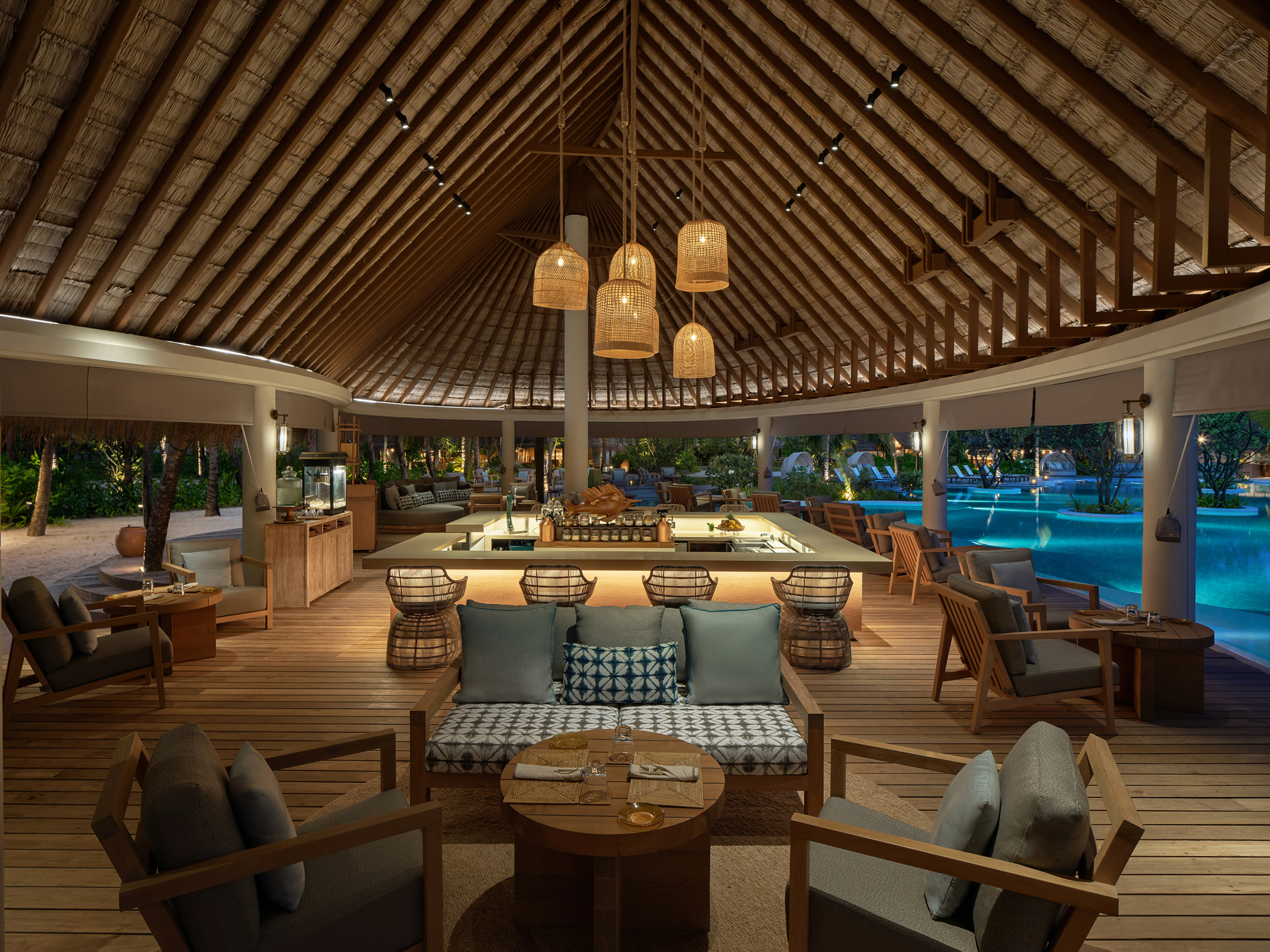 Open kitchen and interior of Sip and Sand restaurant lit up for the evening at Six Senses Kanuhura