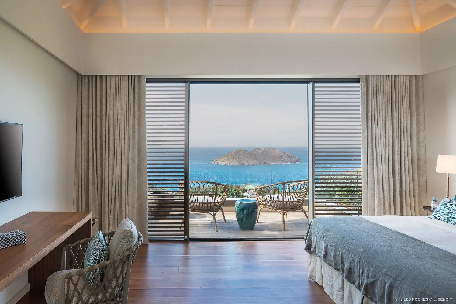 Luxury ocean‑view bedroom at Les Roches Villa in St Barths with sliding doors opening to a private terrace overlooking the Caribbean Sea.