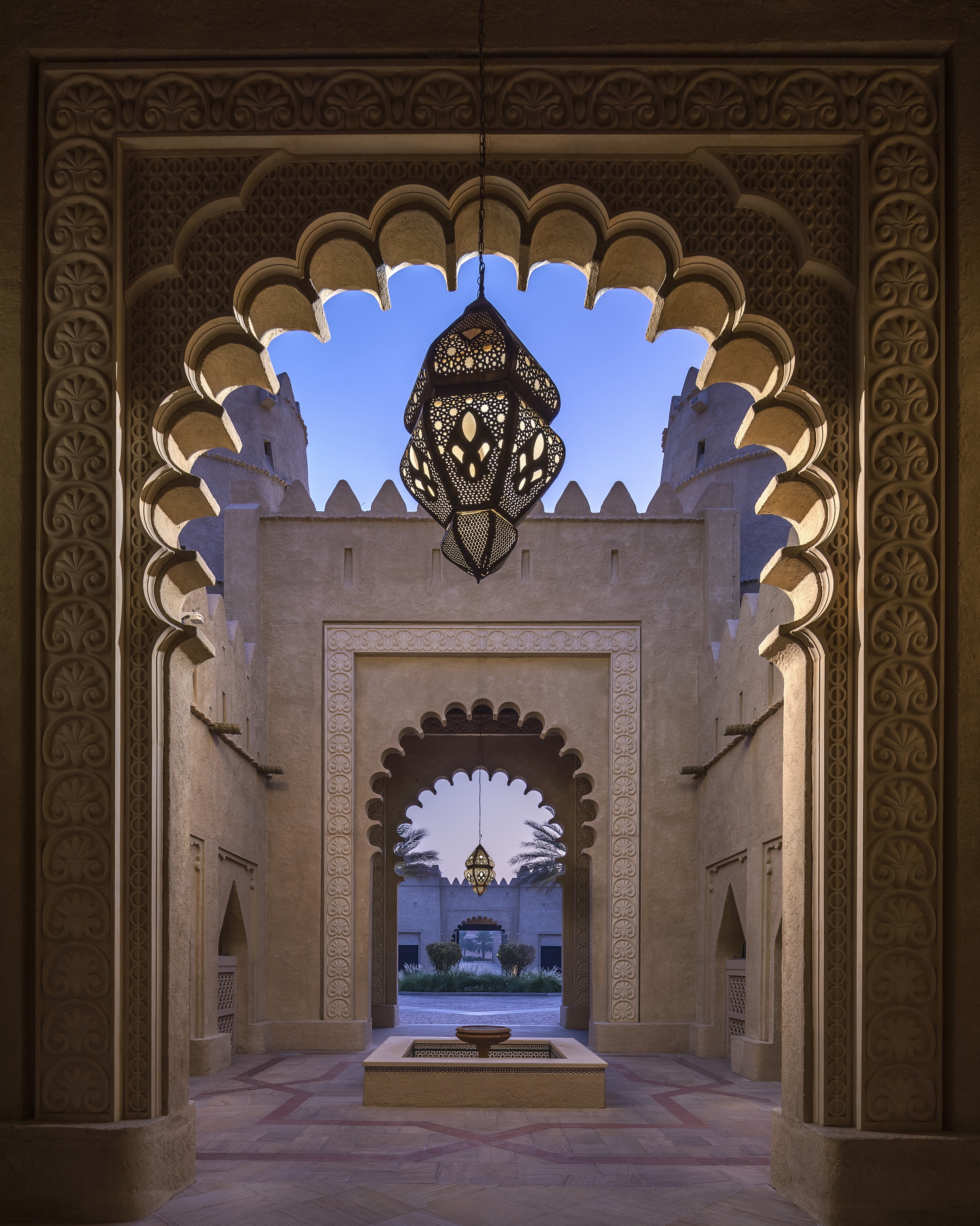 Ornate archways with patterned lanterns leading to a courtyard at Qasr Al Sarab Desert Resort By Anantara