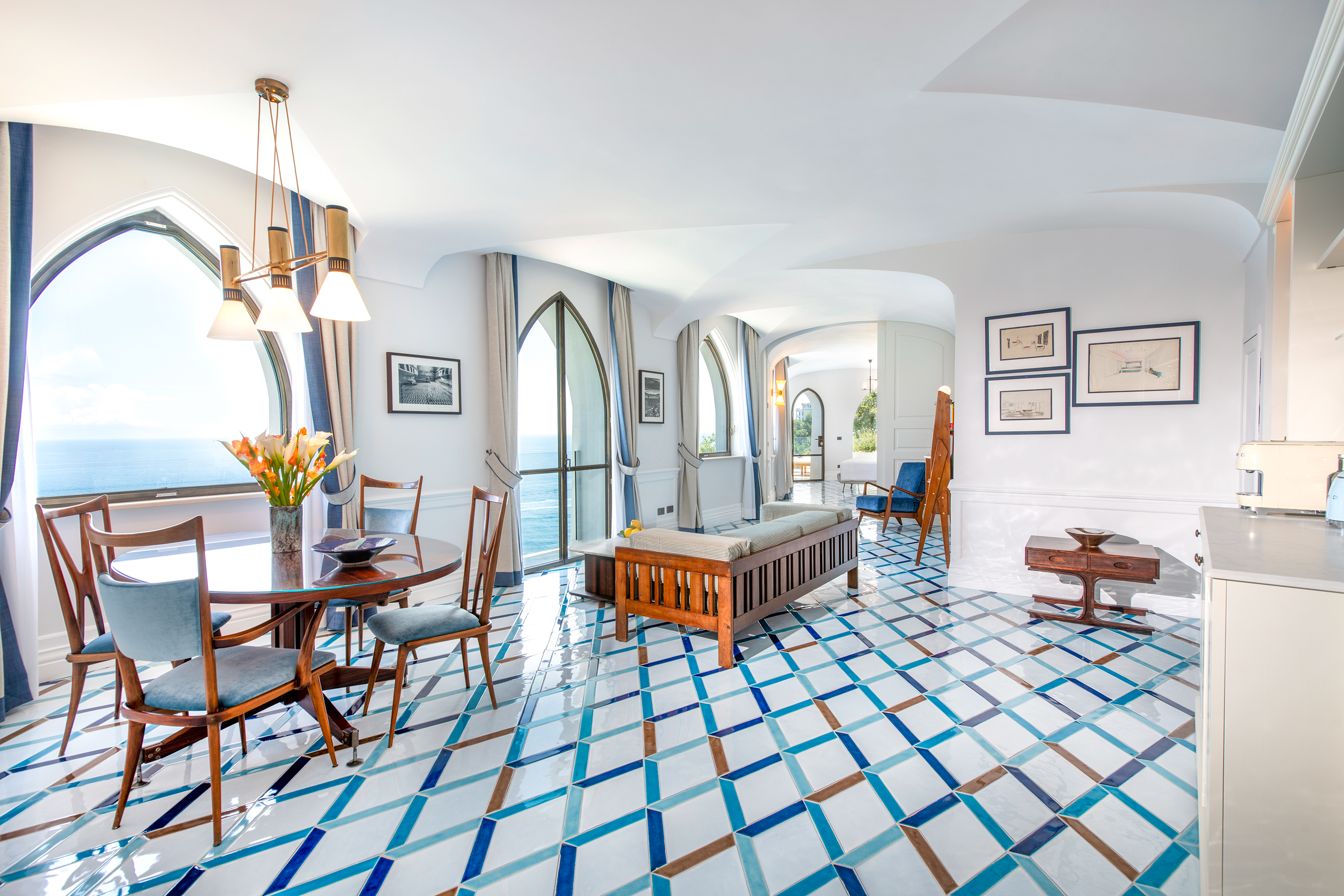 Elegant living and dining area of a Premium Pool Suite at Borgo Santandrea in Amalfi featuring arched windows and stunning ocean views.