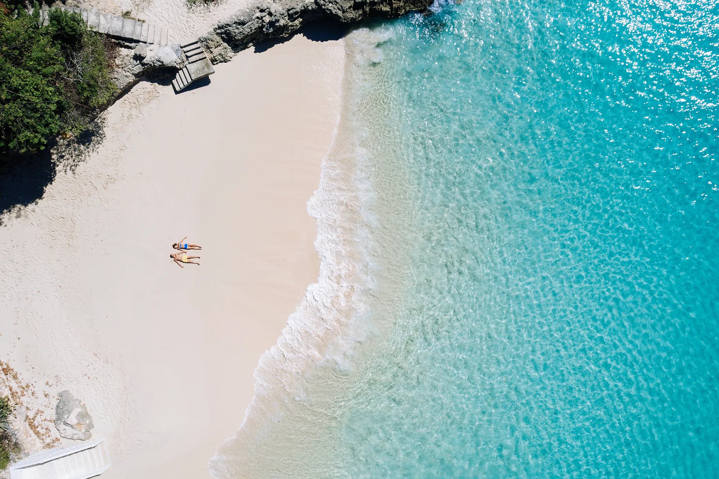 Aerial view of a secluded white-sand beach at Malliouhana, Anguilla, with crystal-clear turquoise Caribbean waters and a tranquil coastal setting