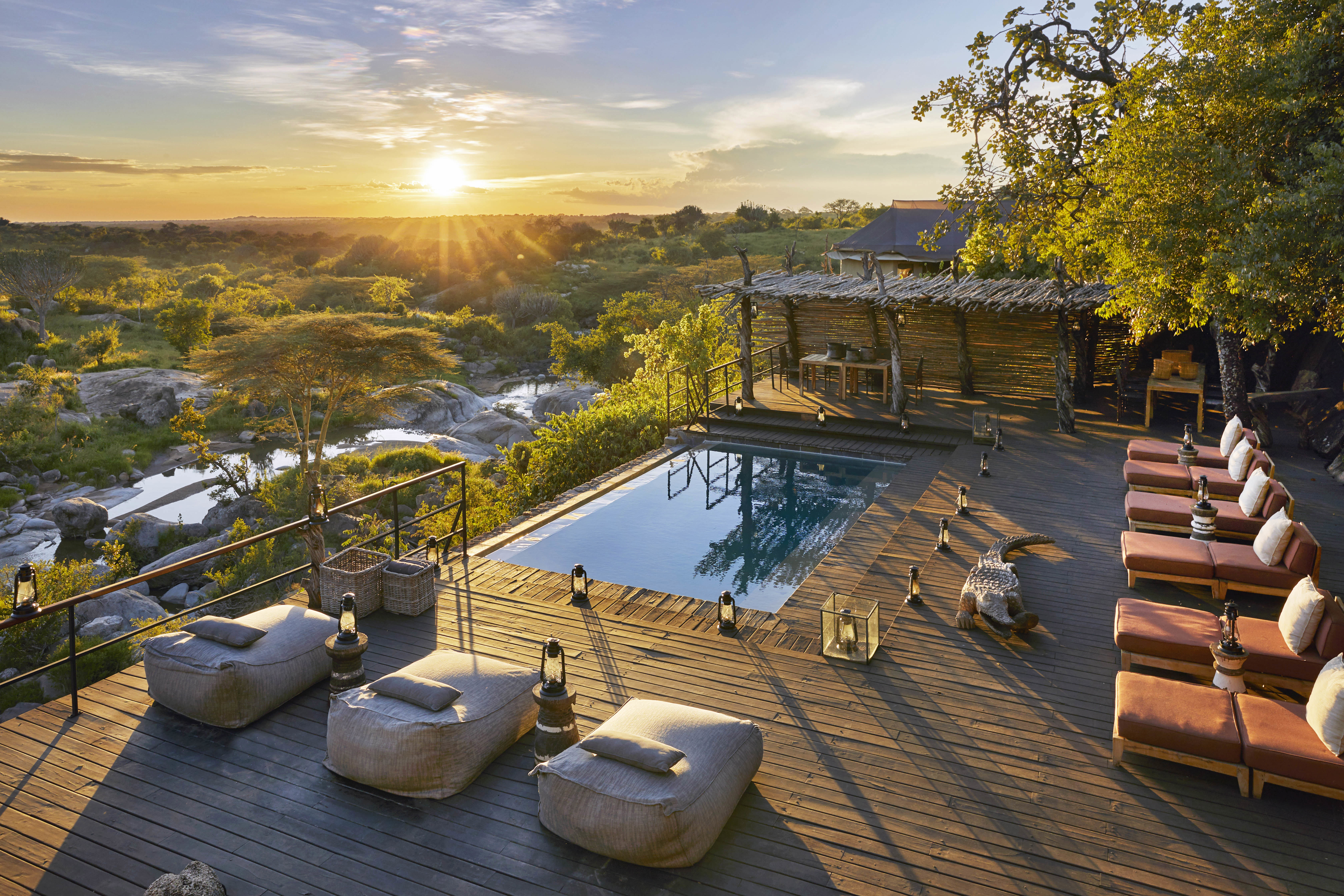 The stylish pool area of Mwiba Lodge with an infinity pool surrounded by loungers at sunset