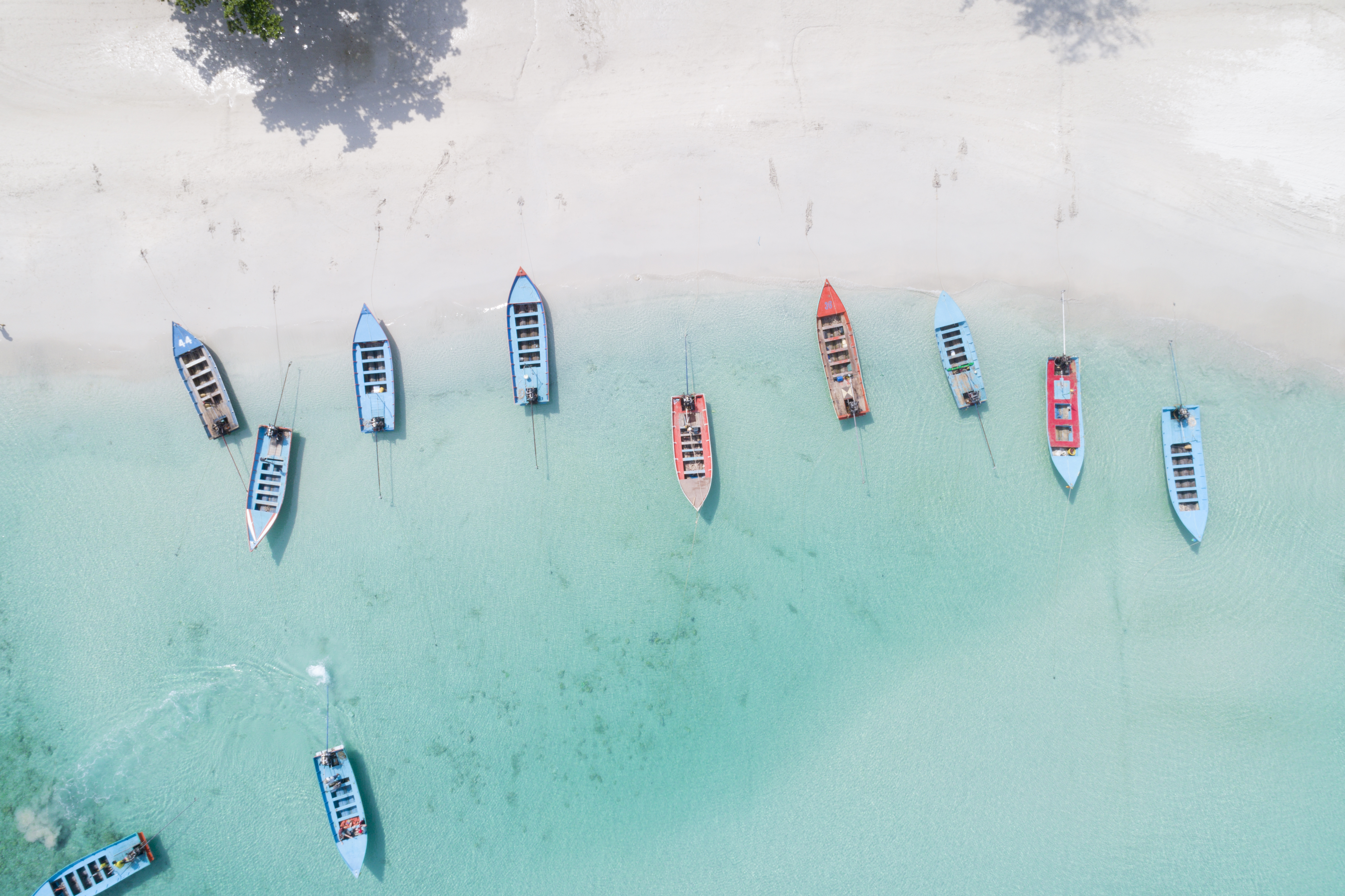A birds eye view of small colourful boats in shallow water