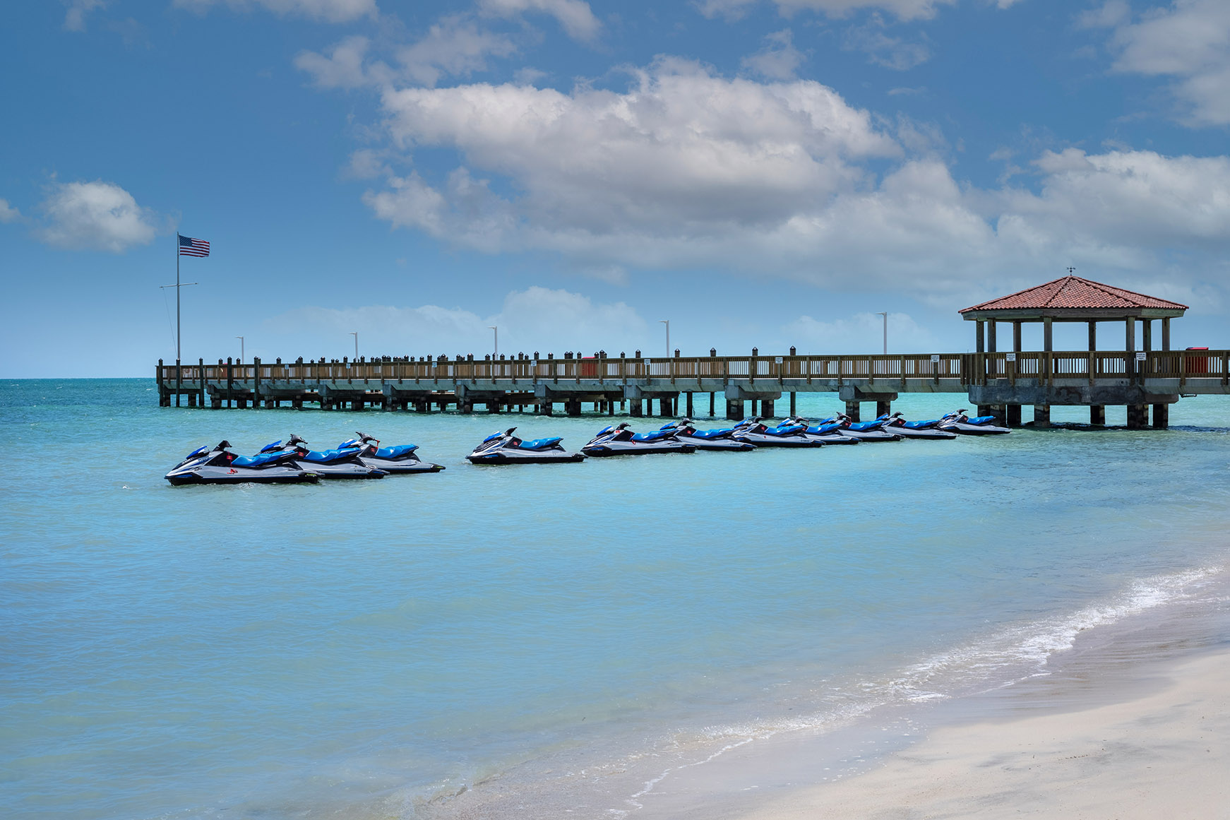 A row of jet skis in the sea beside the activity pier at Casa Marina Key West, Florida