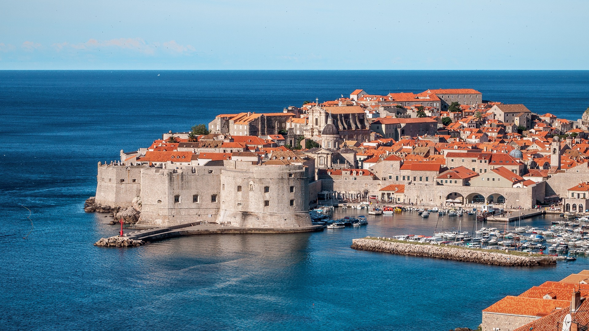 An aerial view of Dubrovnik taken from the water, with its medieval walls and buildings and red roofs