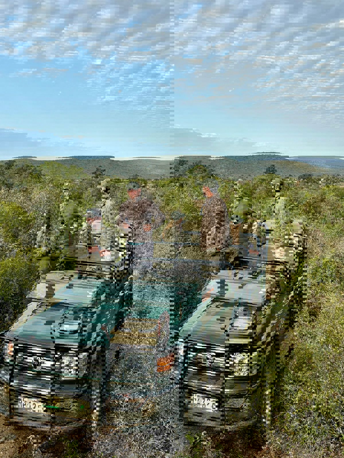 Green jeep with five people on a conservation drive parked in the land of Kwandwe Private Game Reserve