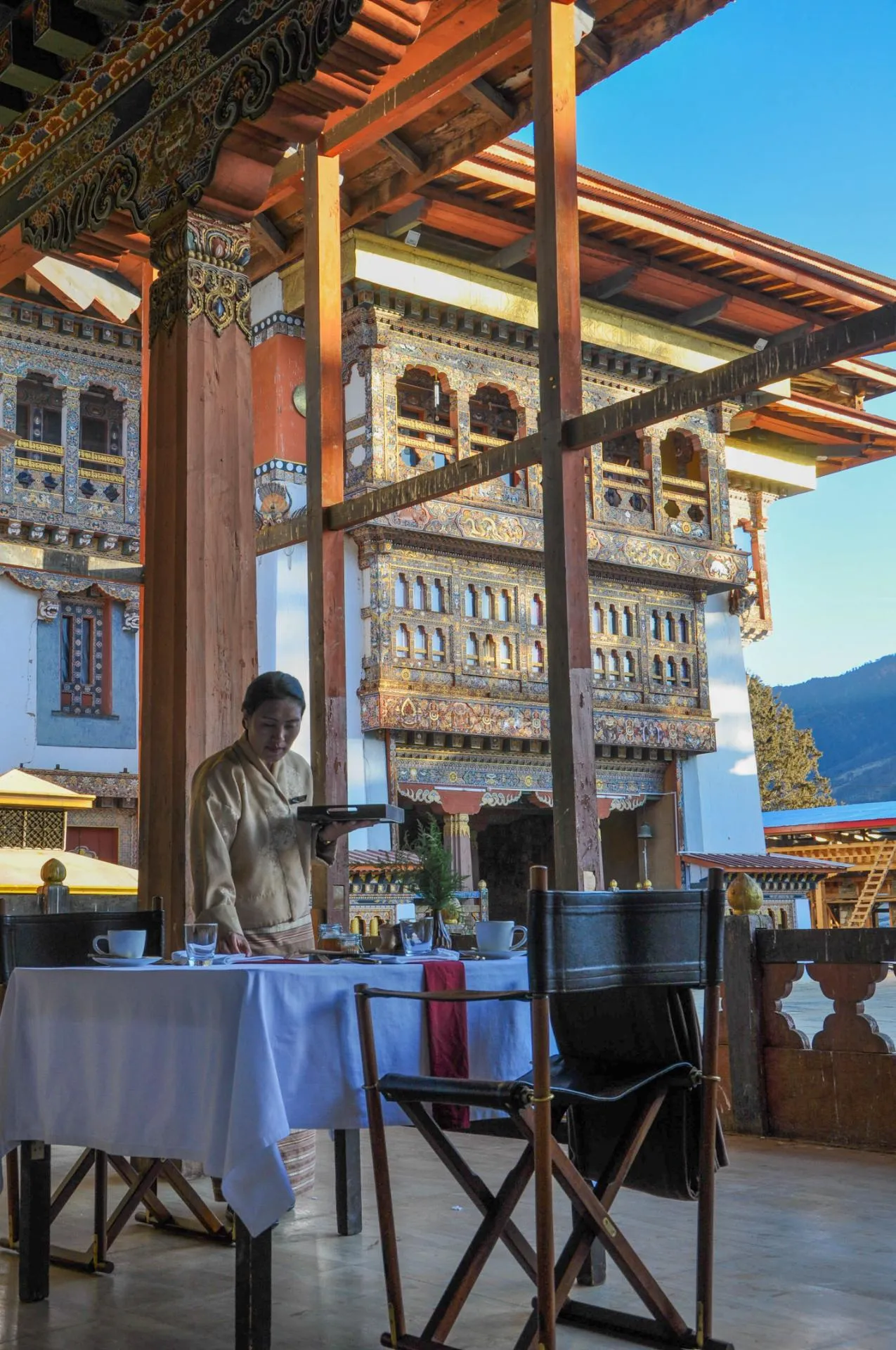 Breakfast service on a terrace with traditional architecture and ornate detailed façade.