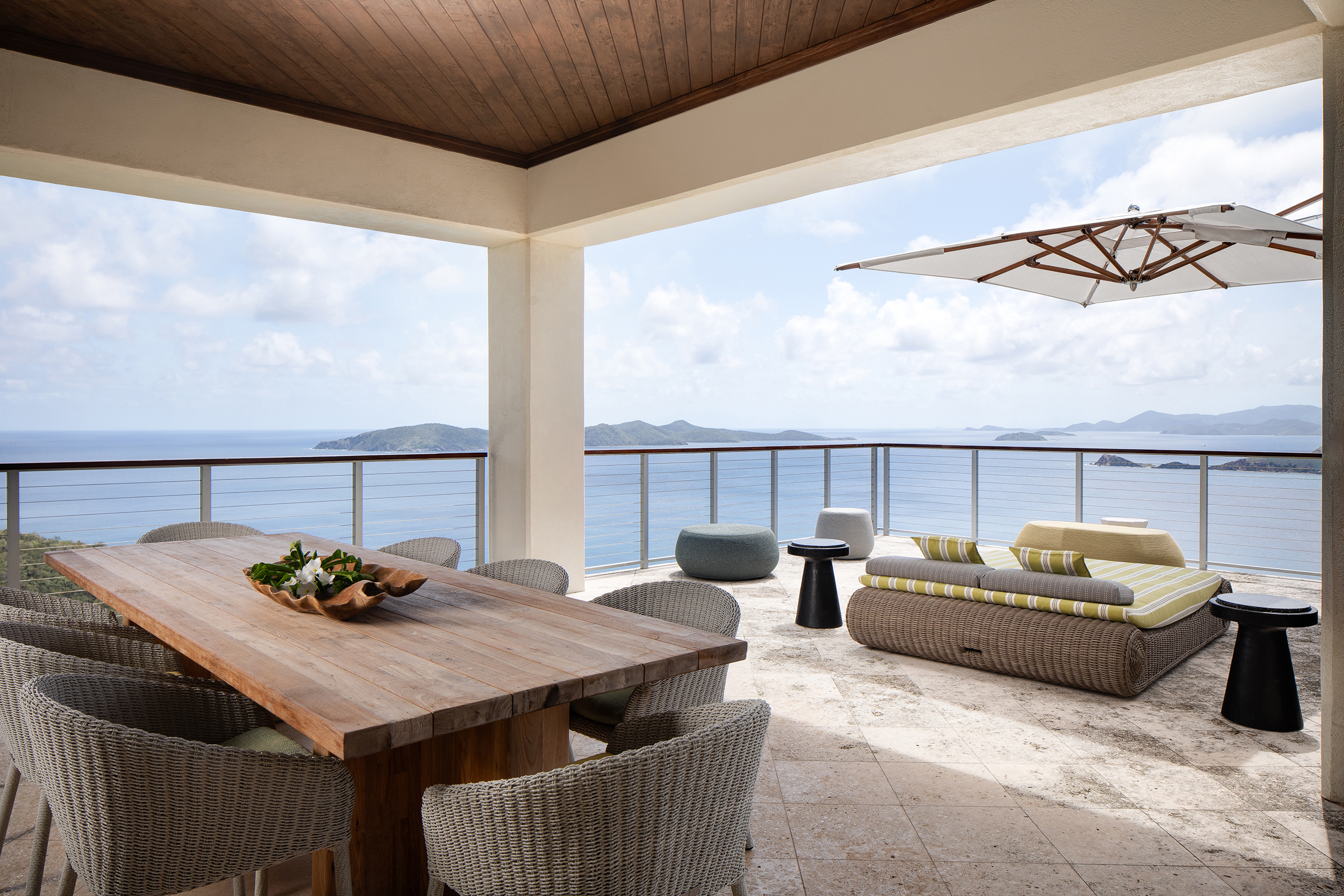 Half covered top floor terrace with dining table, sun lounger and umbrella looking out to sea