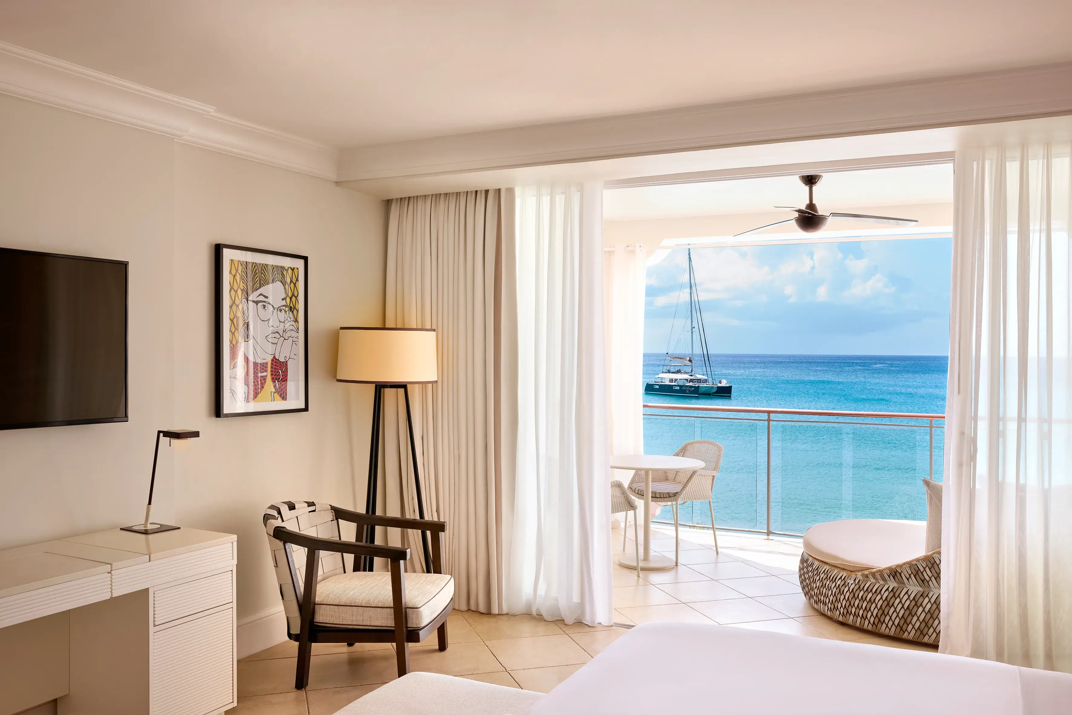Luxury Oceanfront Room at Fairmont Royal Pavilion Barbados featuring elegant Caribbean-inspired interiors, a private balcony, and breathtaking views of the turquoise Caribbean Sea and a yacht