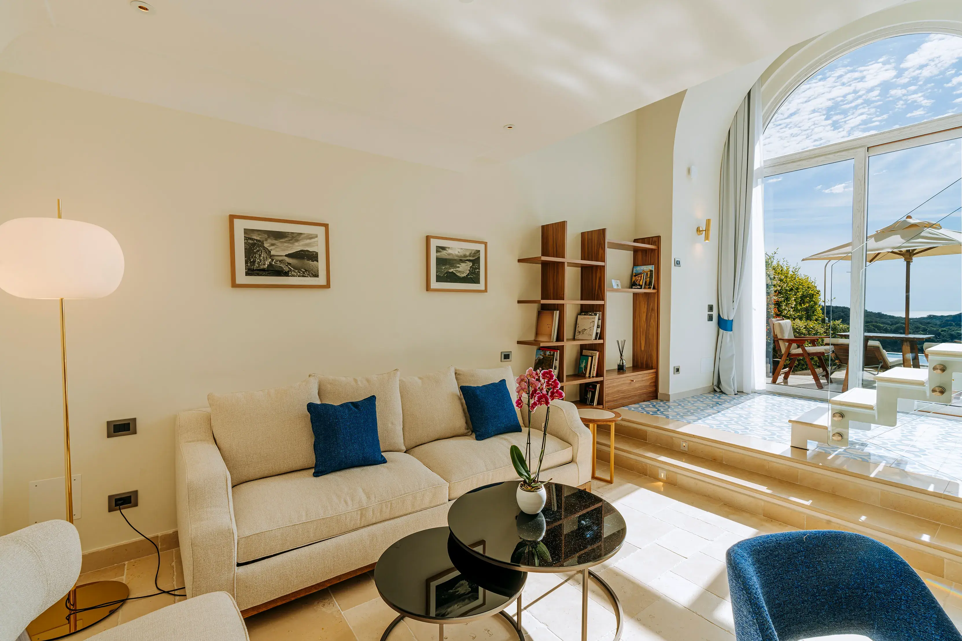 Bright and airy living room of a suite at San Montano Resort on Ischia with modern furniture, large windows, and a scenic outdoor view.