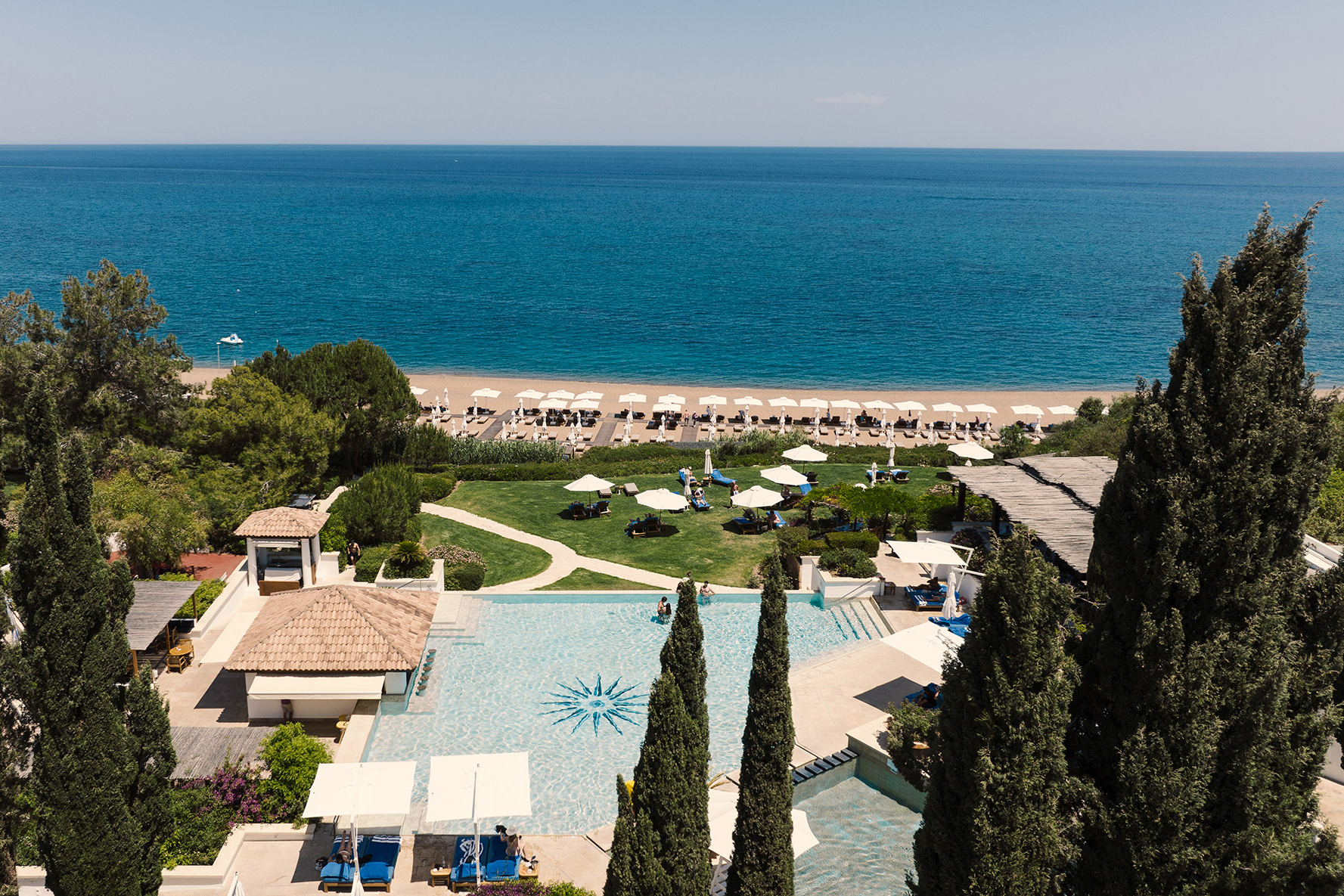 The view out to see from Anassa in Cyprus featuring a swimming pool, garden with sun loungers and a beach lined with more loungers