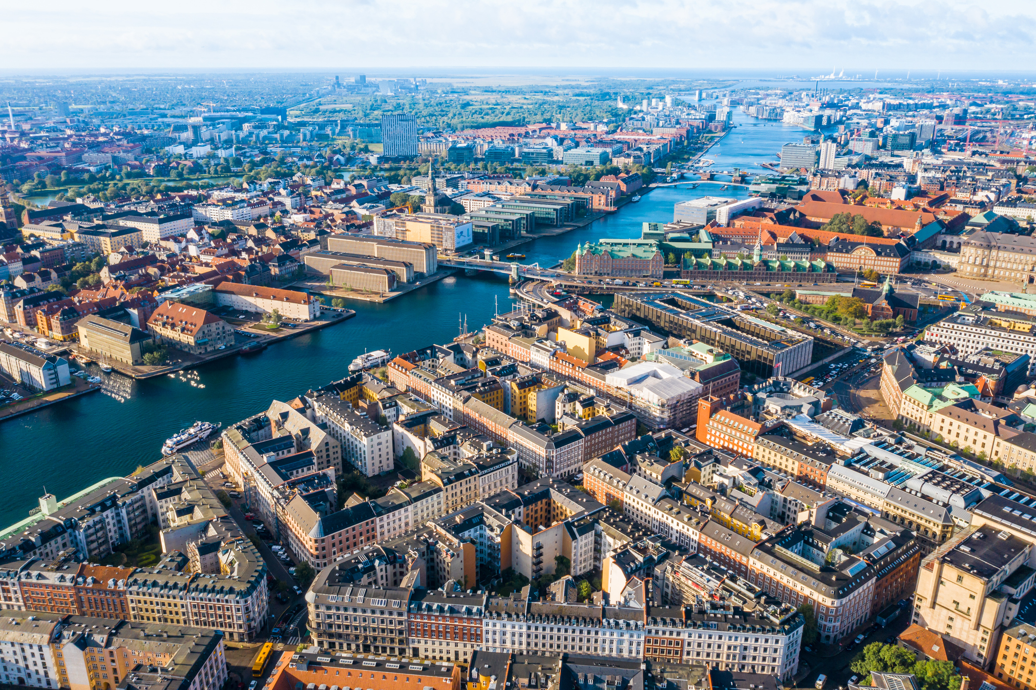 Aerial view of a densely built city with numerous buildings and intersecting waterways under a clear sky.
