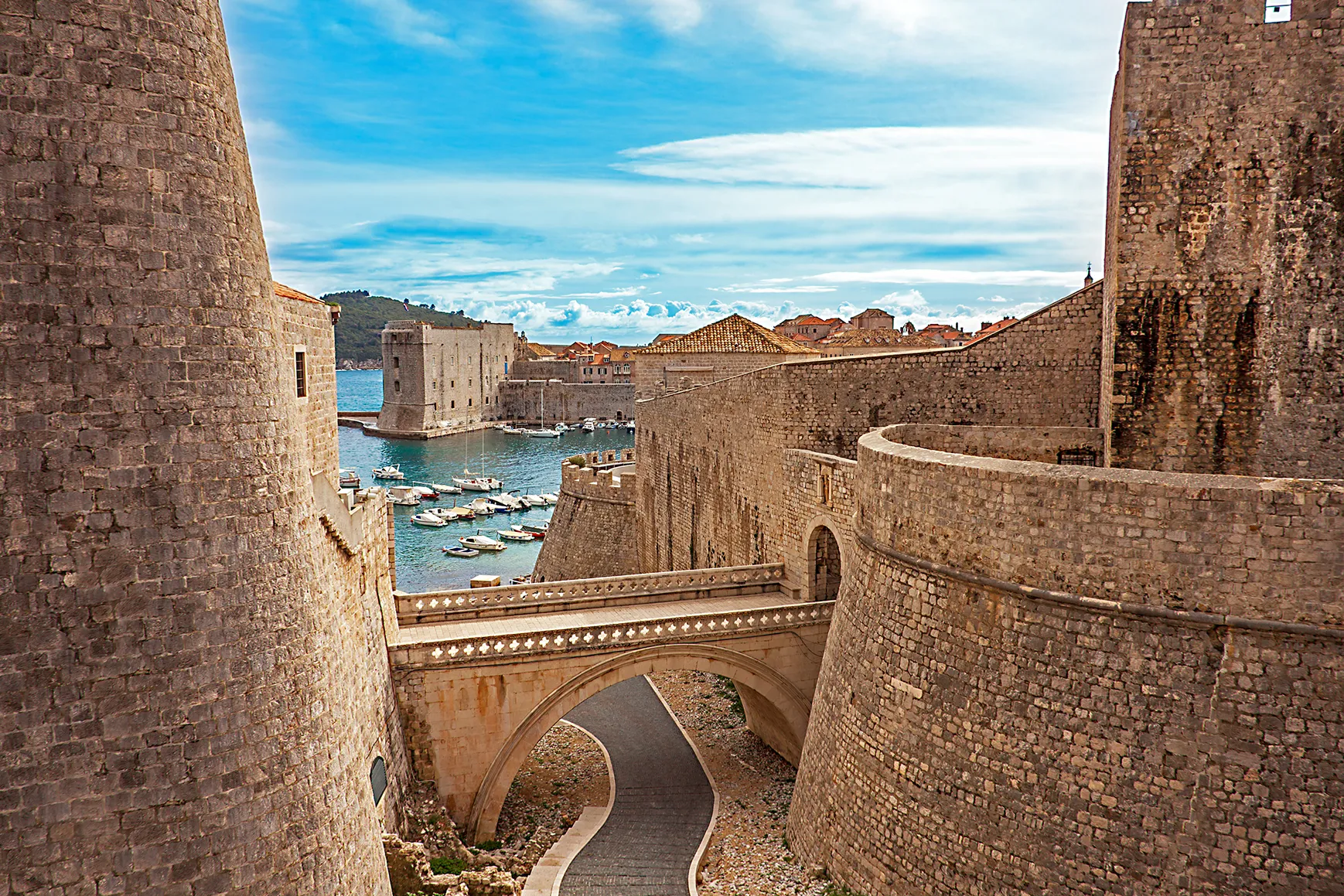 Medieval stone fortress walls and harbor overlooking a coastal old town.