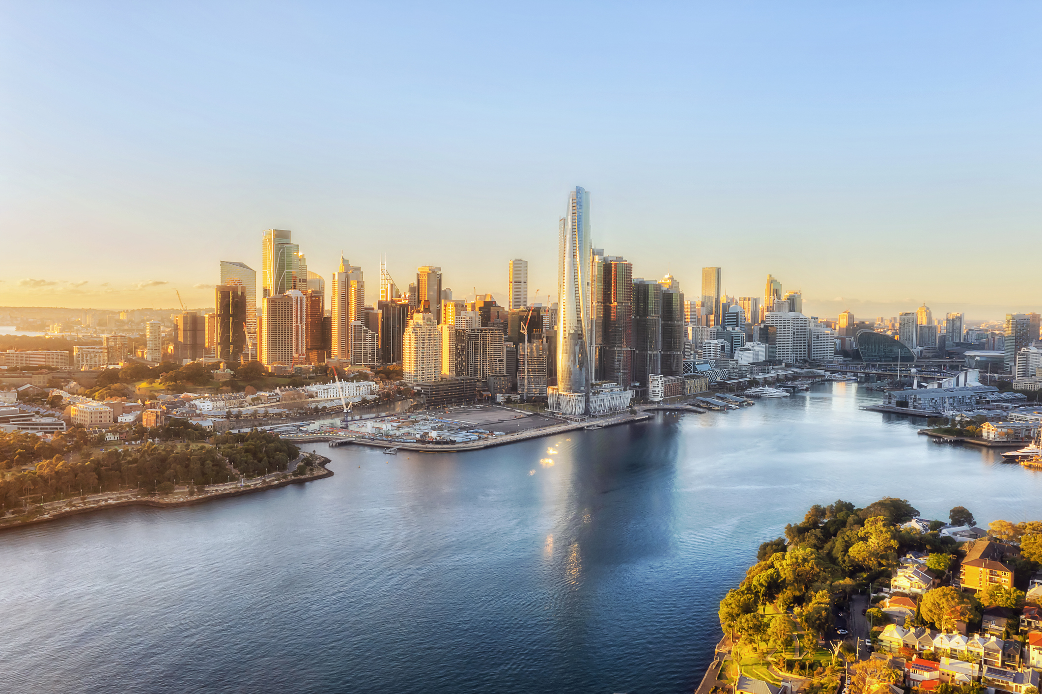 Aerial view of a modern city skyline at sunset with skyscrapers and a riverfront.