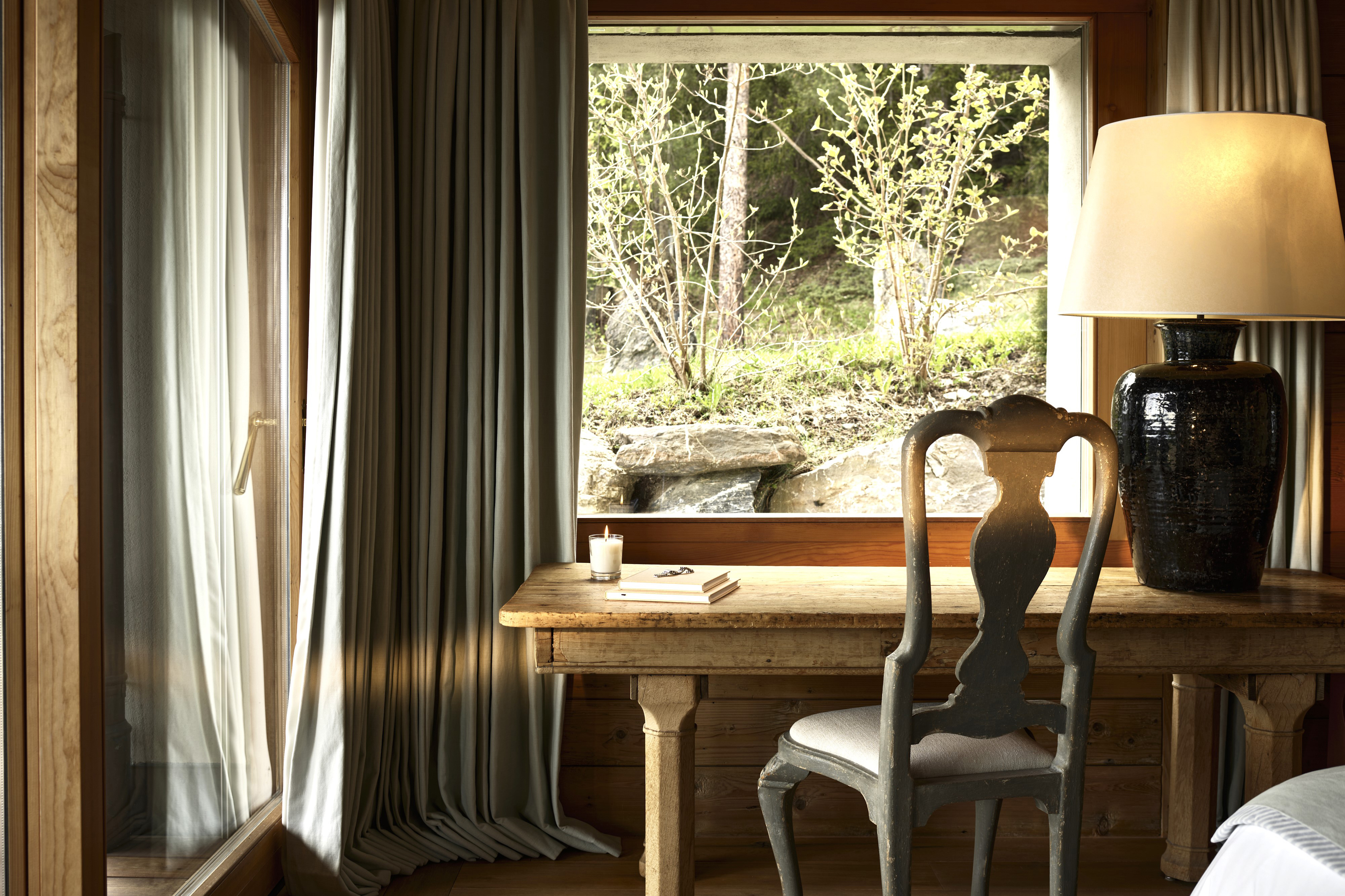 A wooden table and chair with large lamp in the corner of a a Prestige Apartment at LeCrans Hotel & Spa