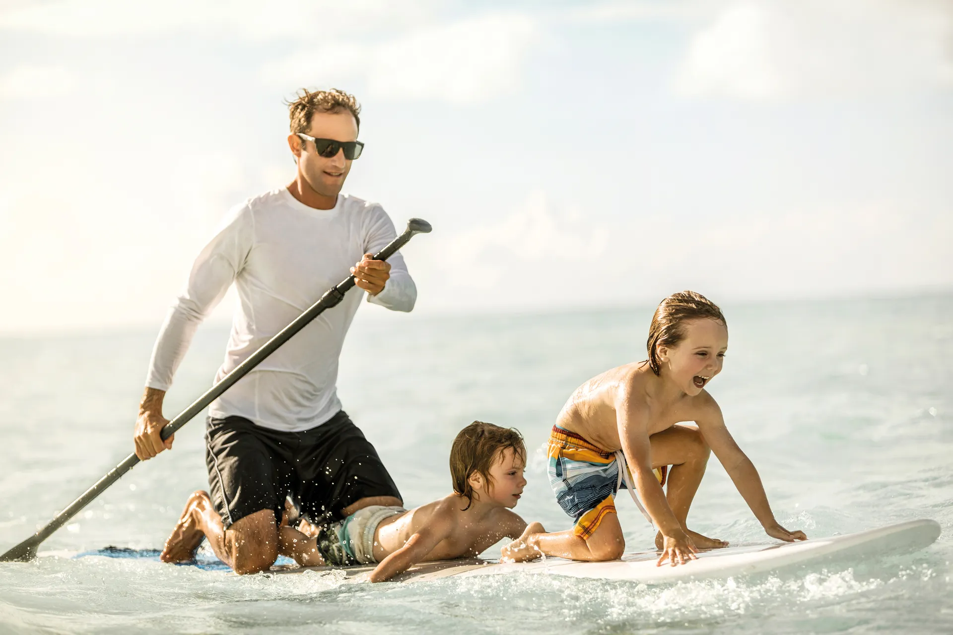 A father and two young sons on a paddleboard